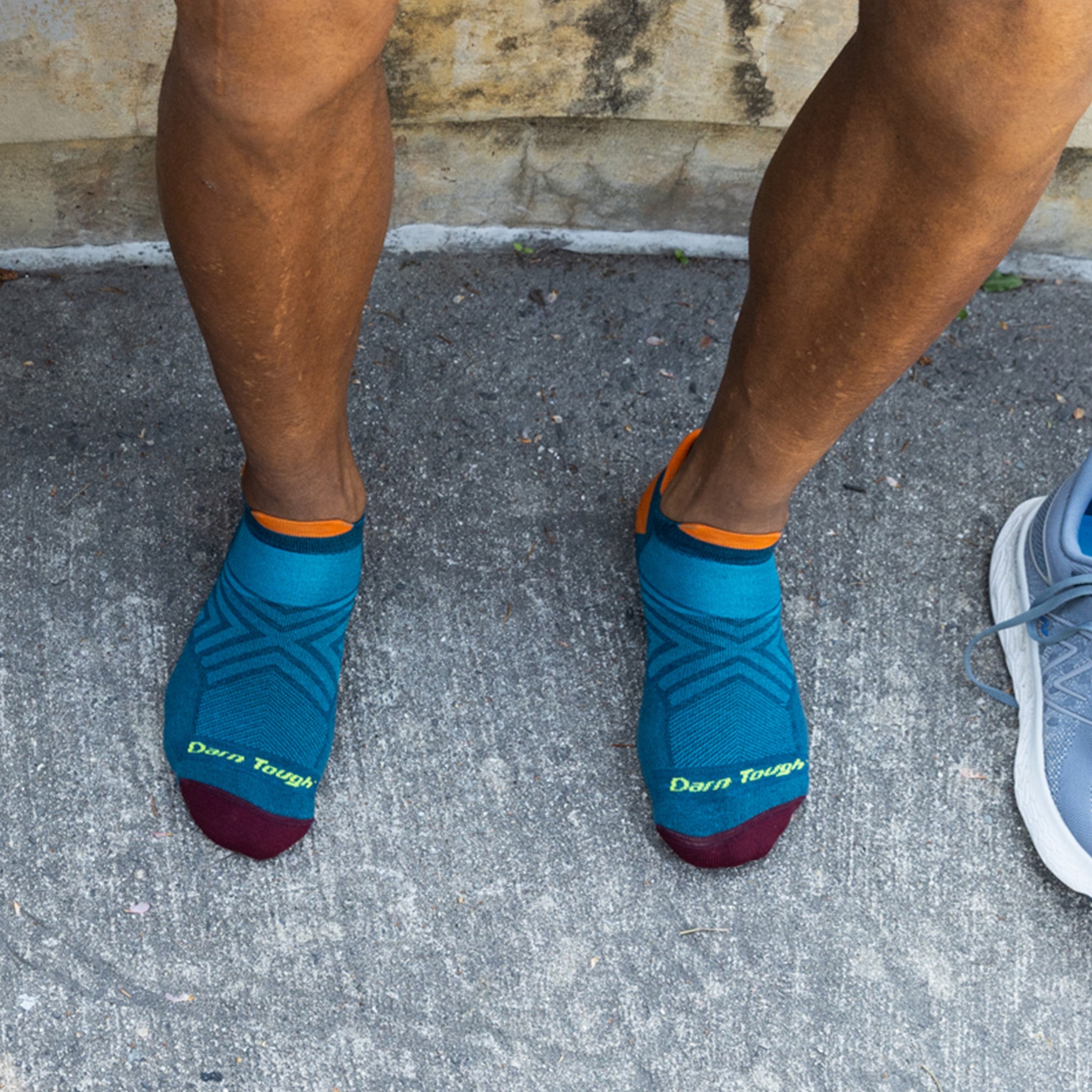 Overhead shot of model sitting outside wearing the men's no show tab running sock in dark teal