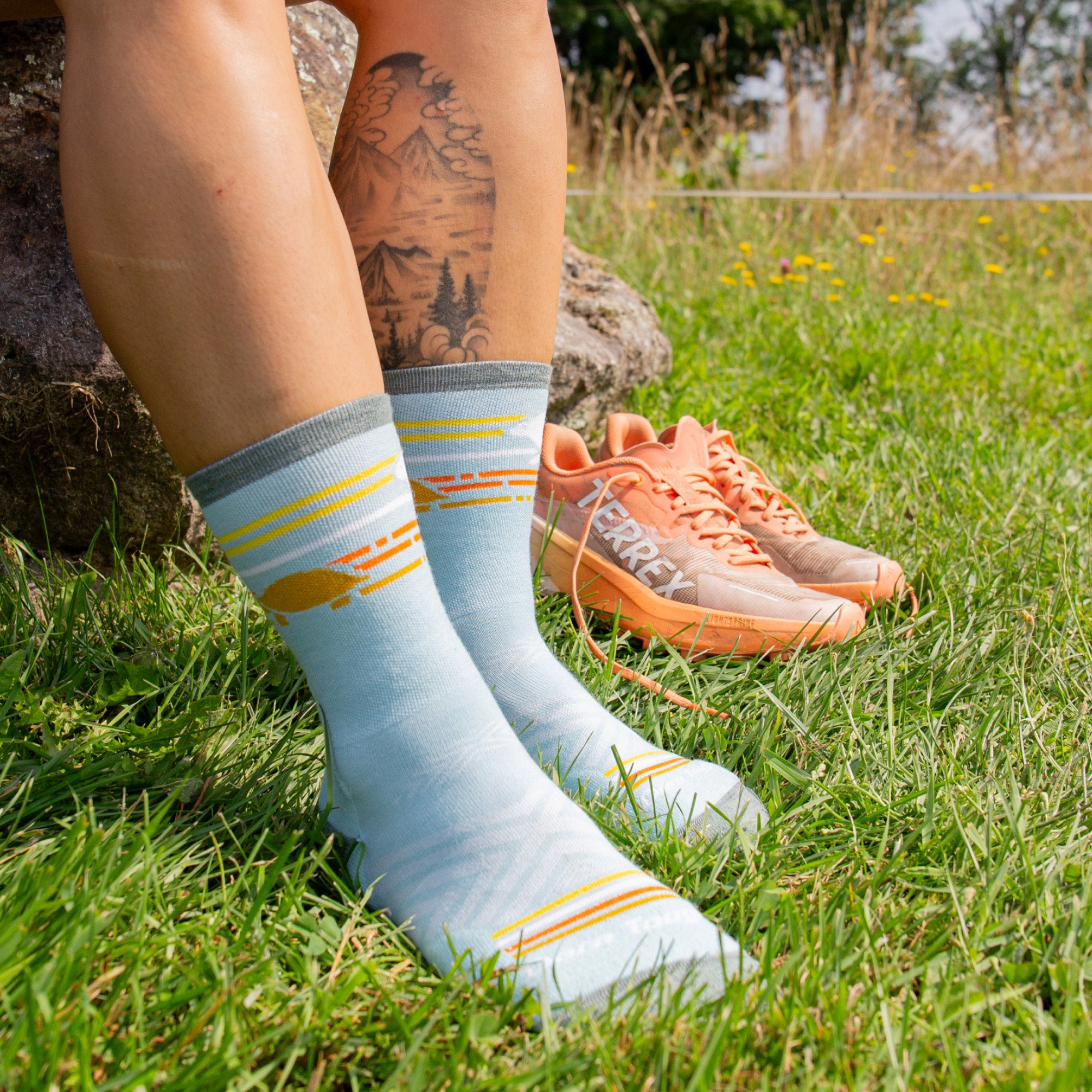 models feet in the grass wearing the 1050 pacer micro crew in glacier with a pair of sneaker in the back ground