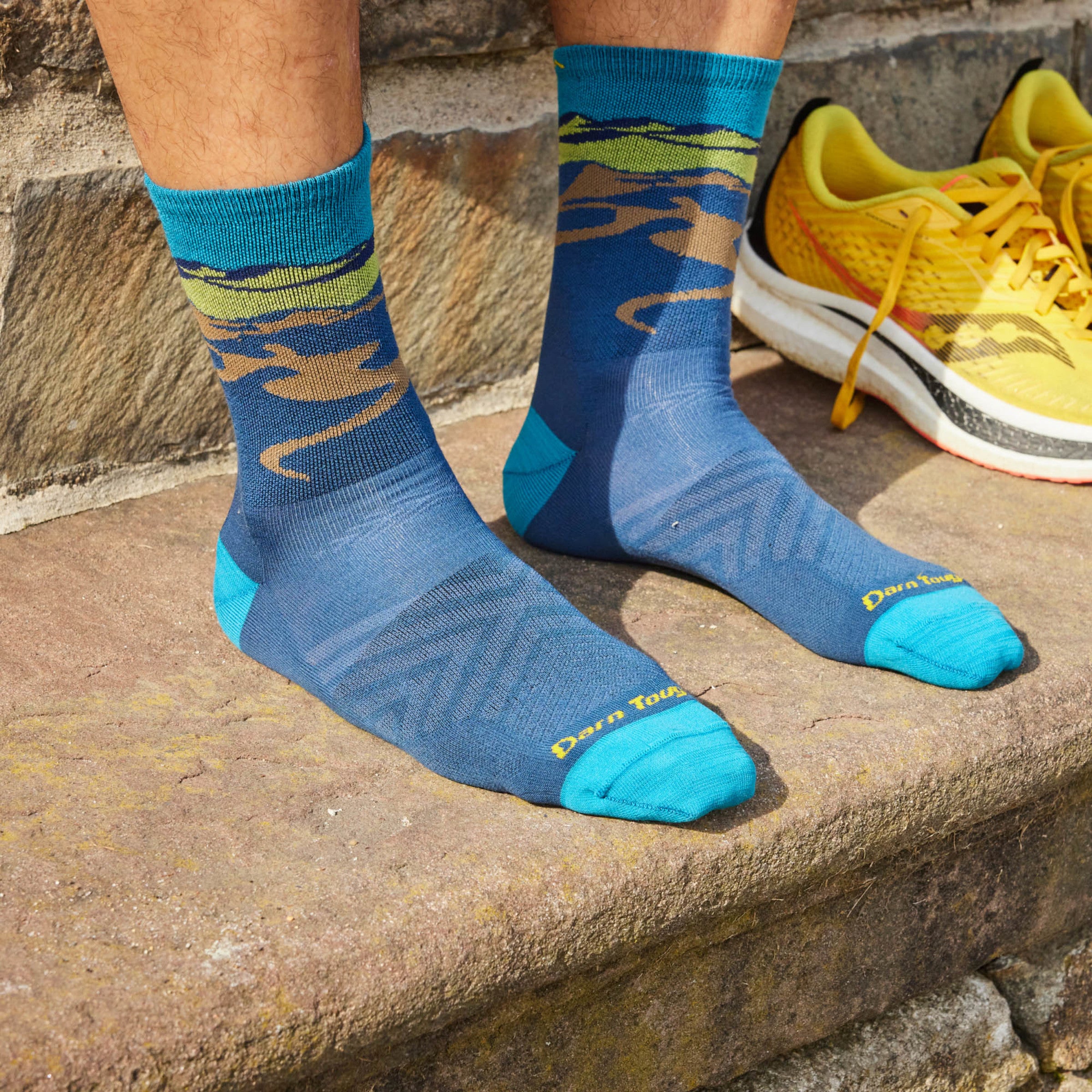 Models feet on stone step wearing the Men's Ridge Runner Micro crew Running sock in Midnight