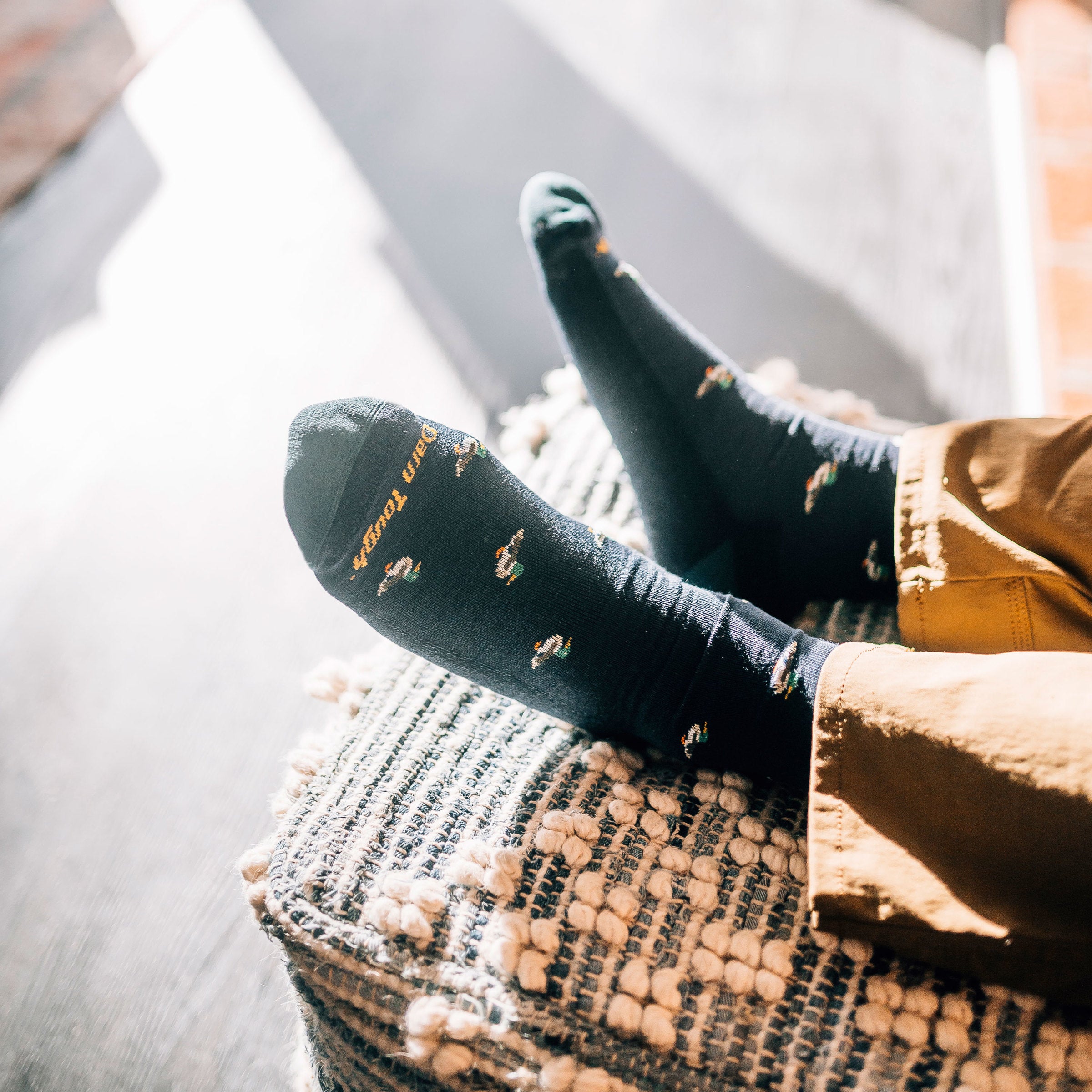 Close up overhead shot of model with his feet up wearing men's duck duck moose crew lifestyle sock in navy eclipse