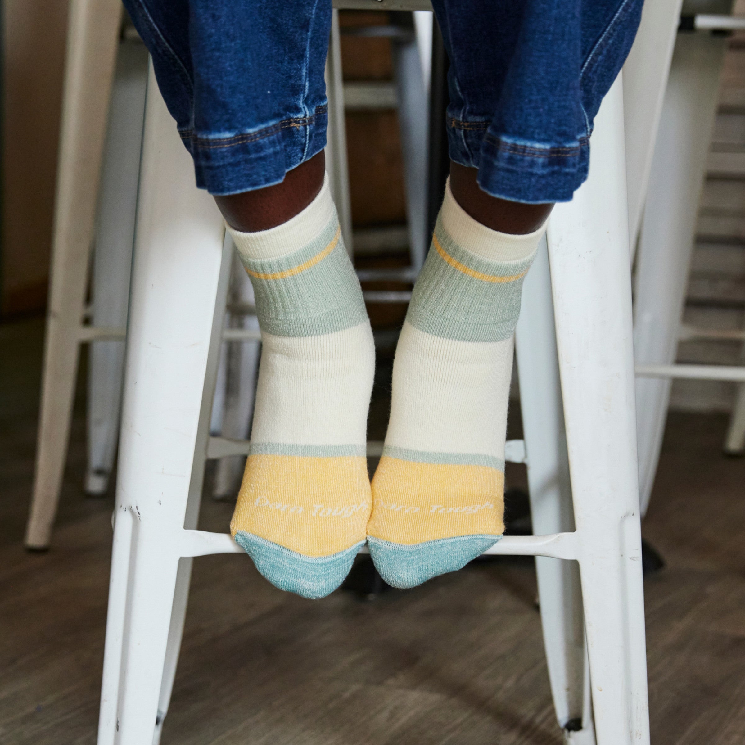close up on model feet on bar stool wearing 6117 pear featuring blue heather toe yellow and cream blocks on foot