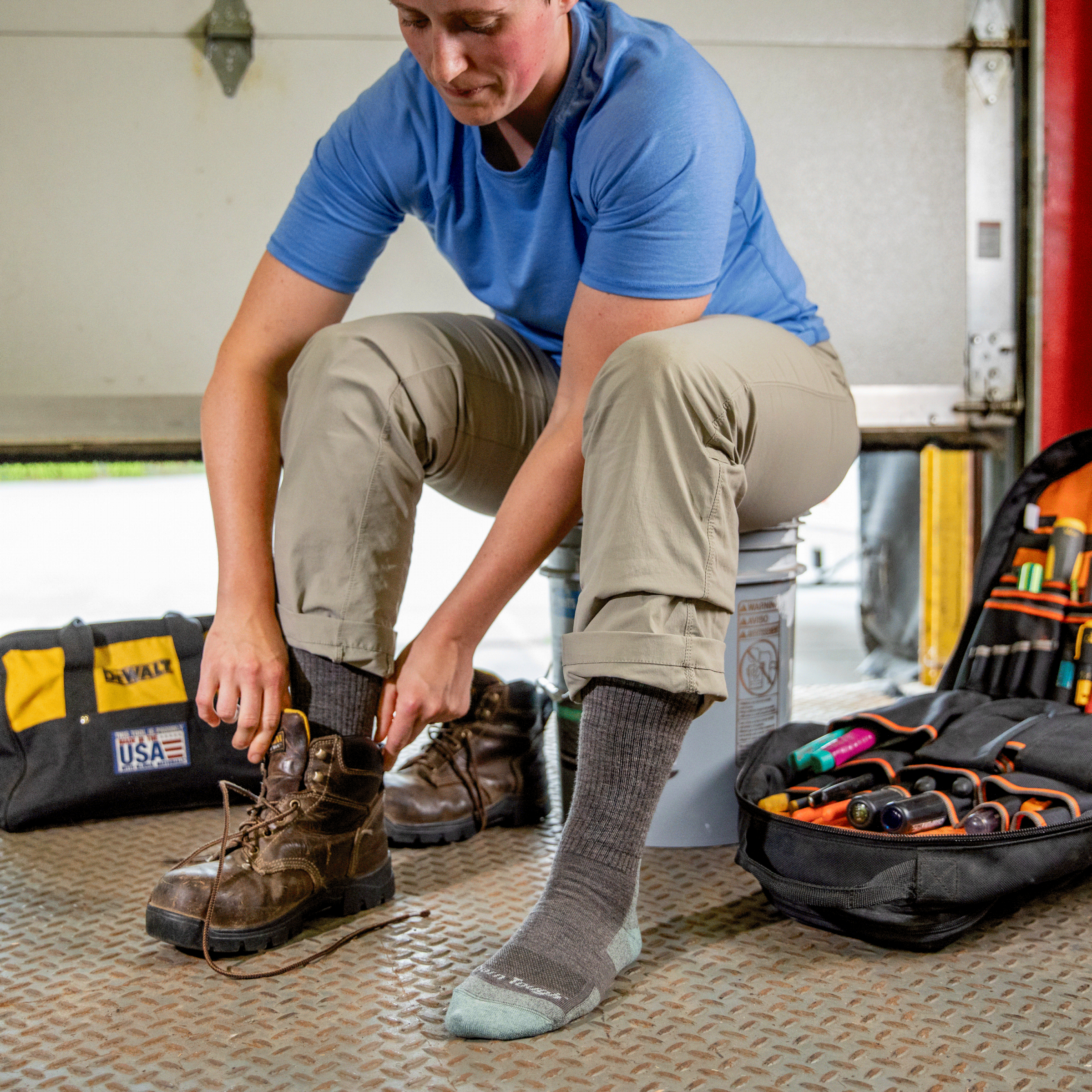 Worker putting on leather work boots over RTR work boot socks in shale