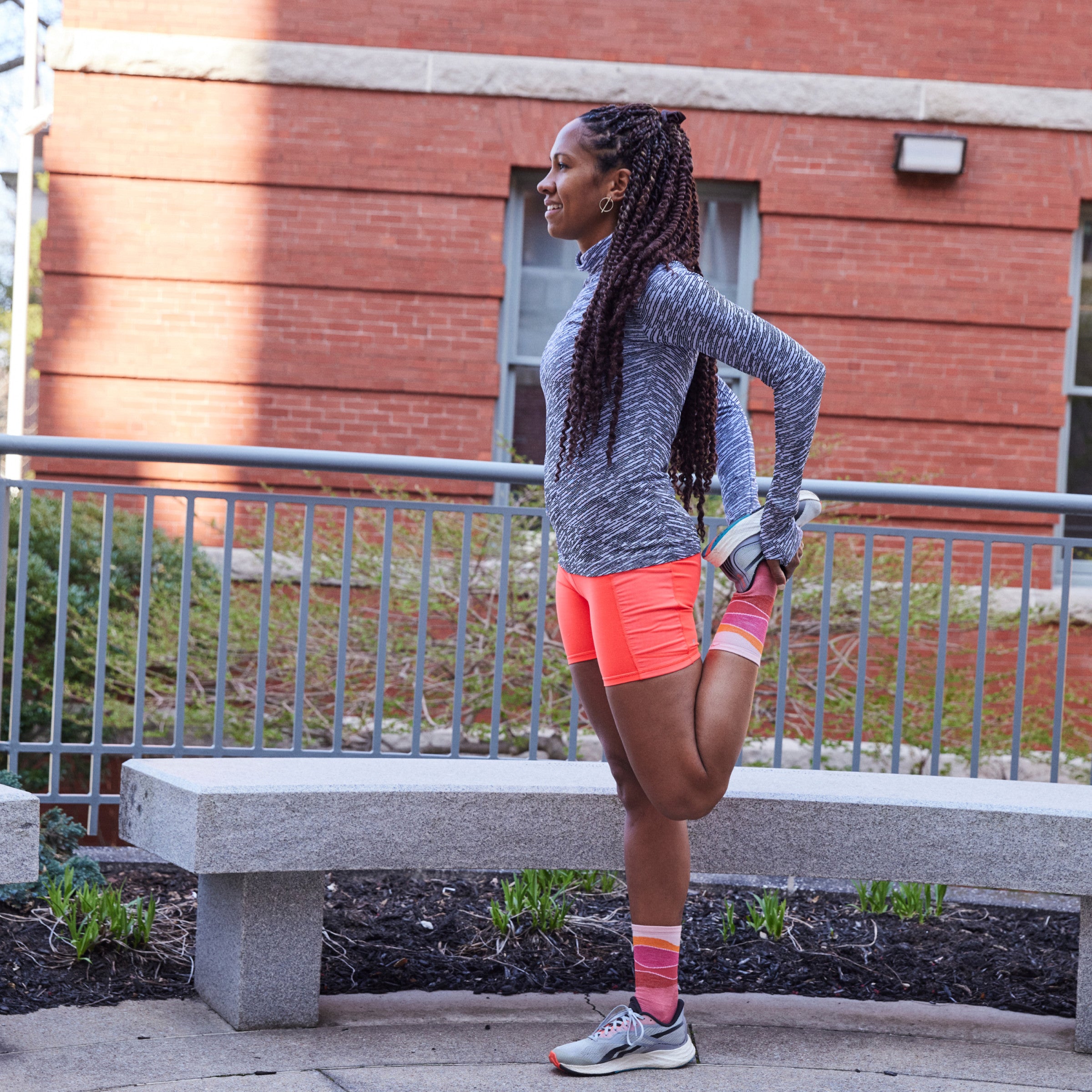 Action shot of model stretching before run wearing 1064 socks in canyon colorway