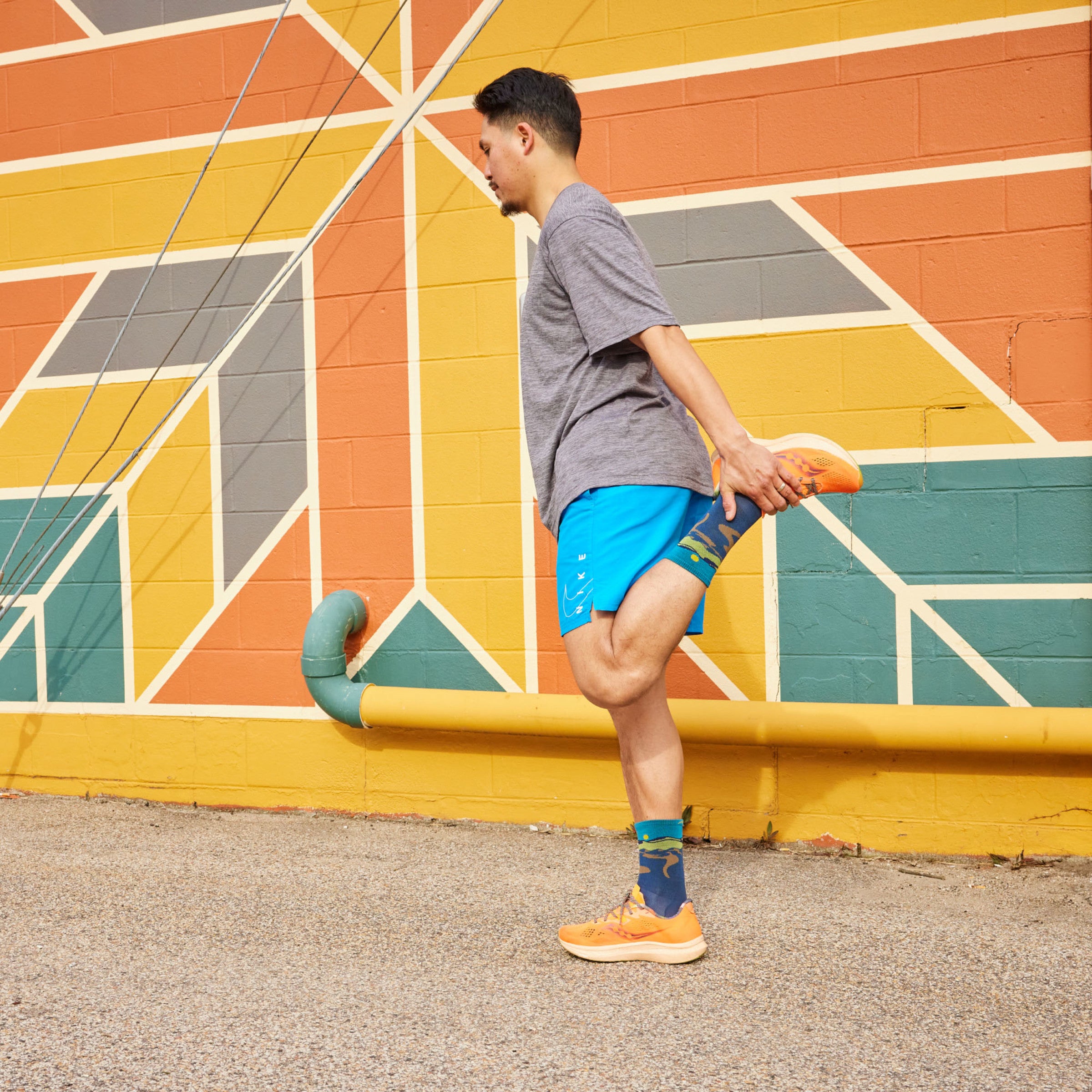 Model standing holding one ankle stretching wearing the 1065 Ridge runner micro crew running sock in Midnight