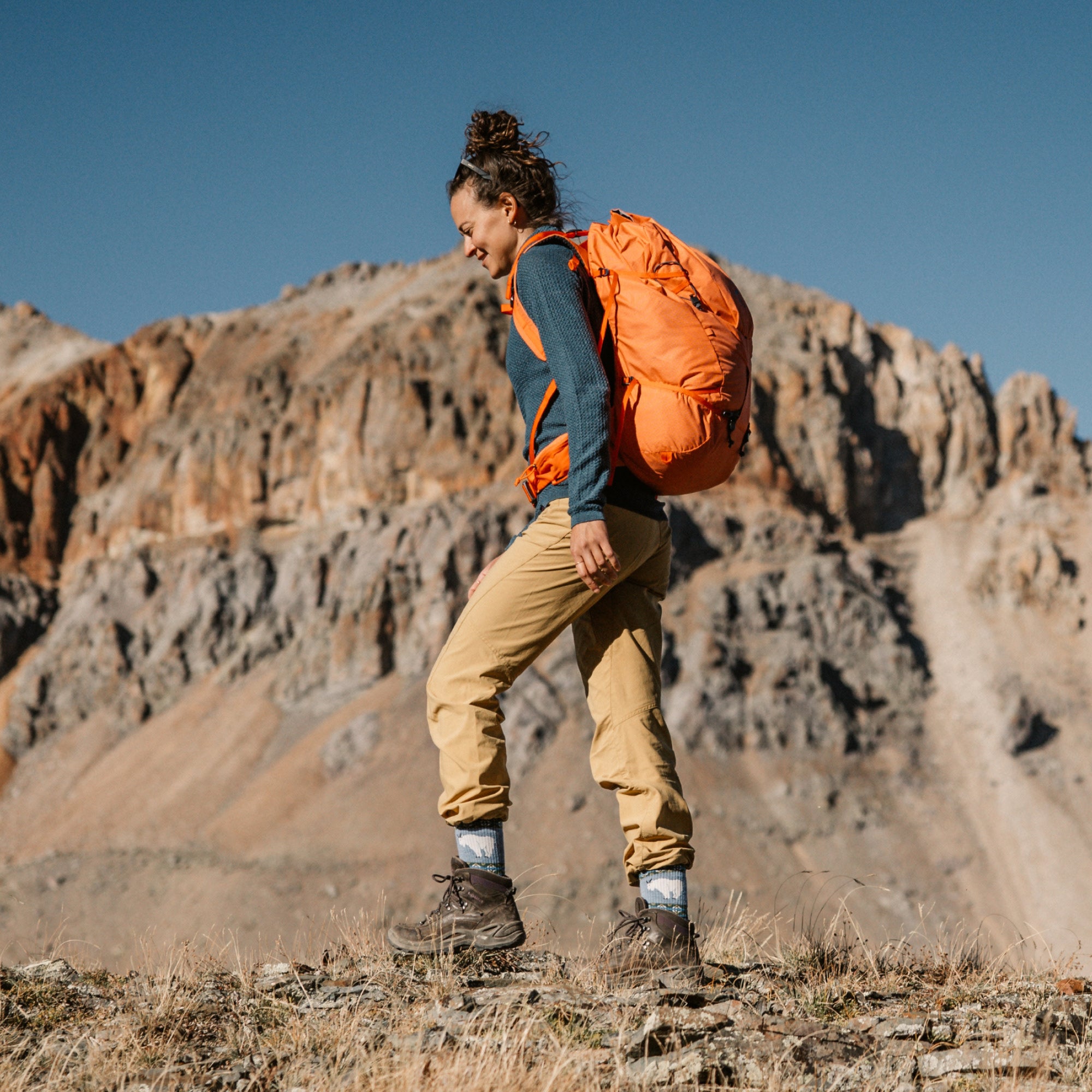 model with orange backpack walking through canyon flat wearing the 5017 vanna grizzle in goat blue