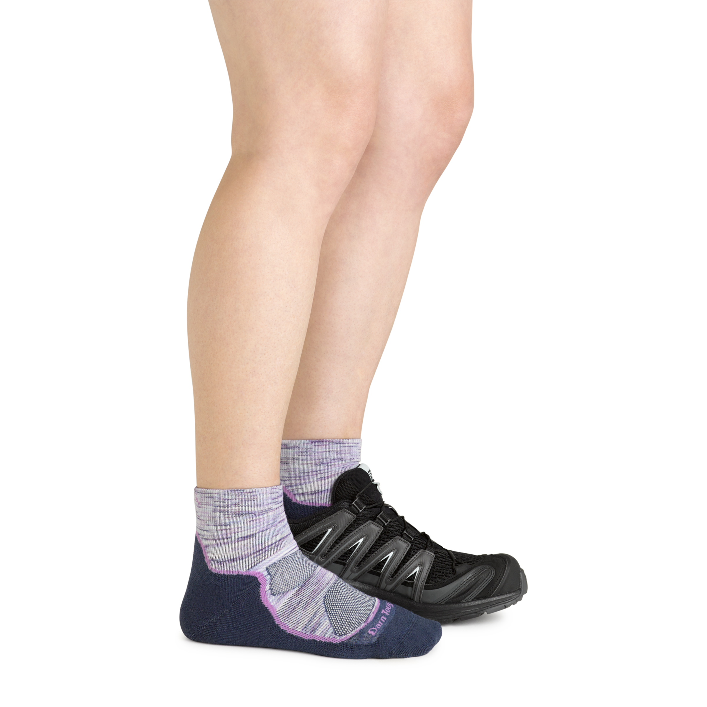 Model wearing the women's light hiker quarter hiking sock in cosmic purple with a black sneaker on her left foot