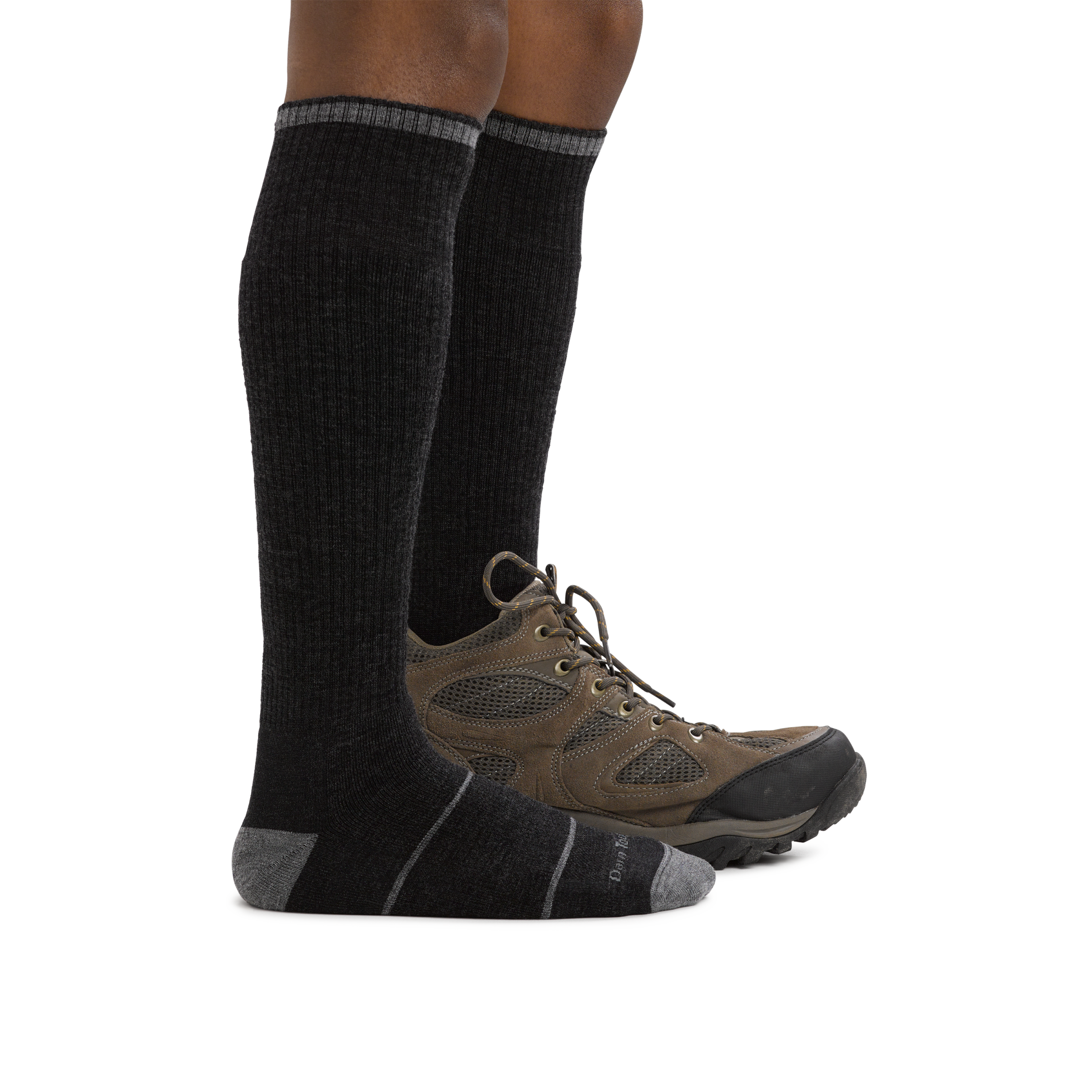 Man standing barefoot wearing Paul Bunyan Over the Calf Midweight Work Sock in Gravel with back foot wearing a boot