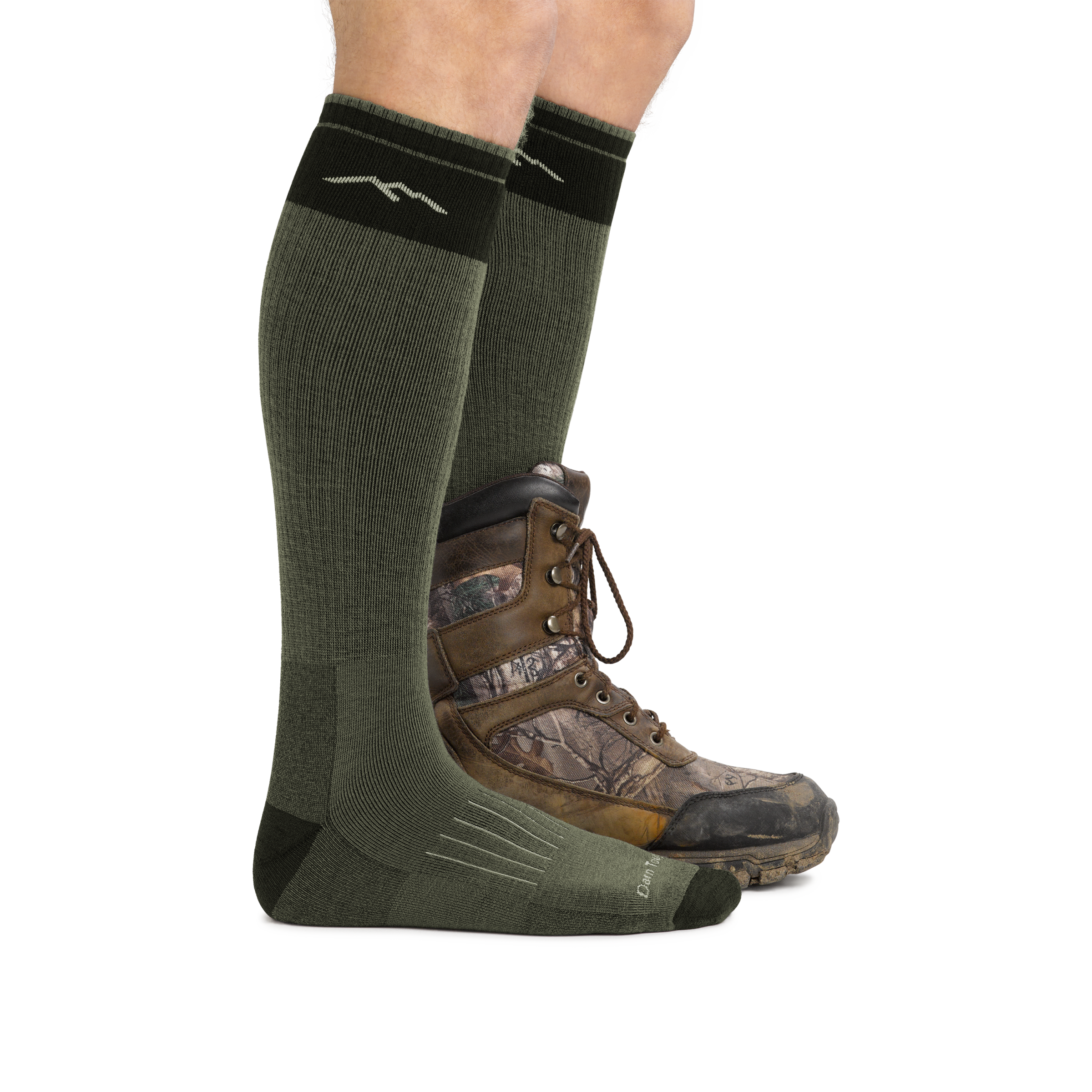 Profile image of a man's legs facing right against a white background wearing Hunter Over the Calf Heavyweight Hunting Socks in Forest with back foot also in a hunting boot