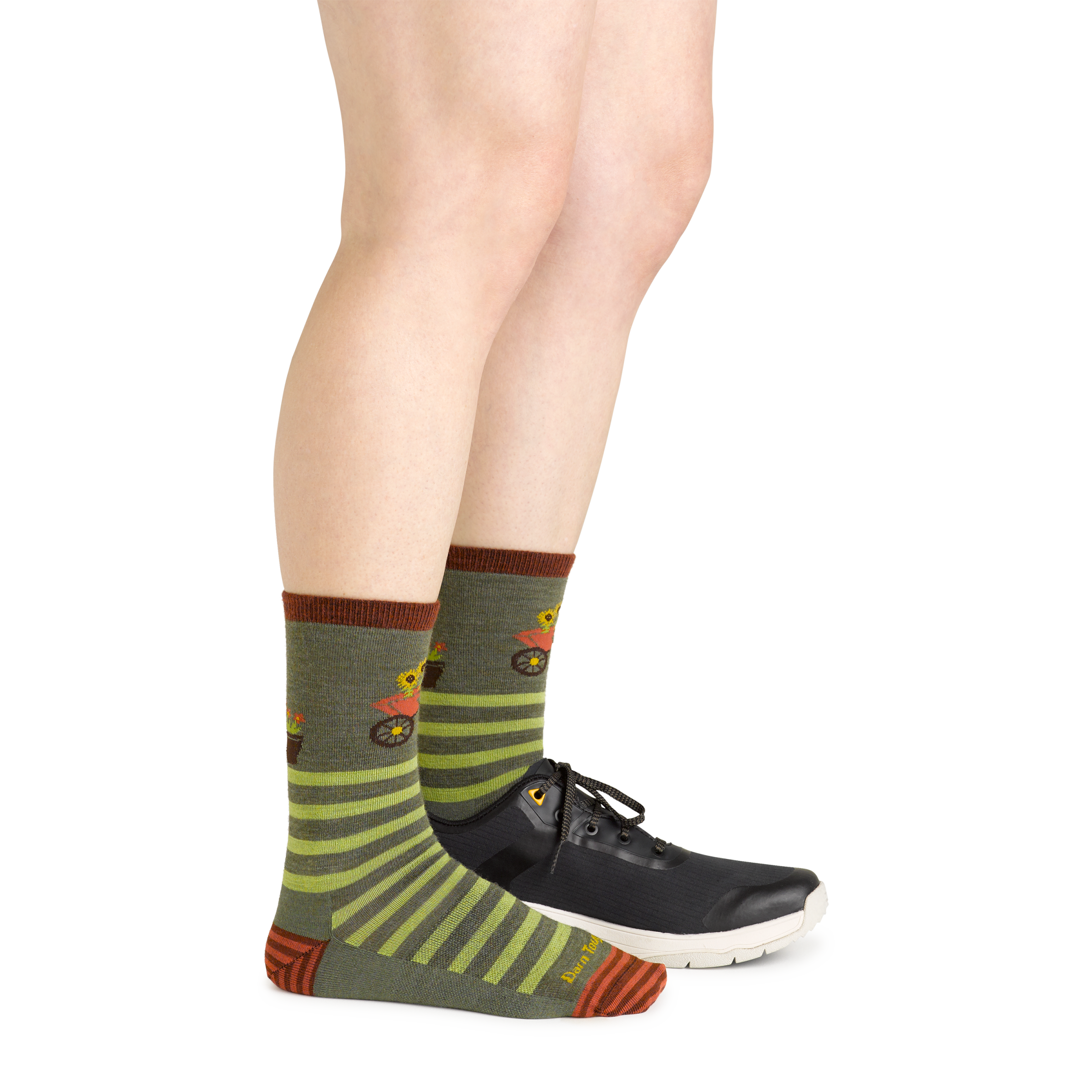 Side studio shot of model wearing women's animal haus crew lifestyle sock in herb green with black sneaker on left foot