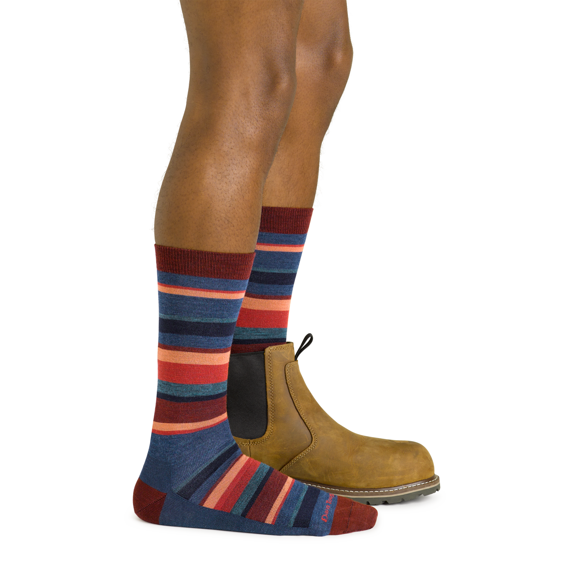 Side studio shot of model wearing men's druid crew lifestyle sock in denim with brown boot on left foot