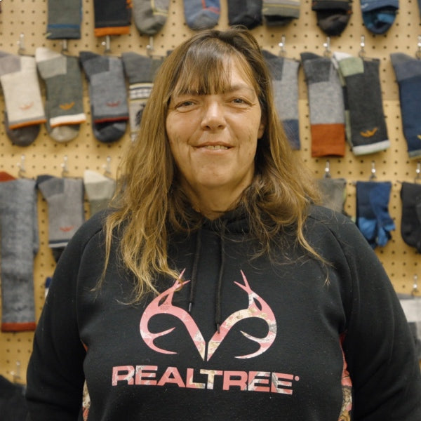 Raelene standing in front of a wall full of Darn Tough socks