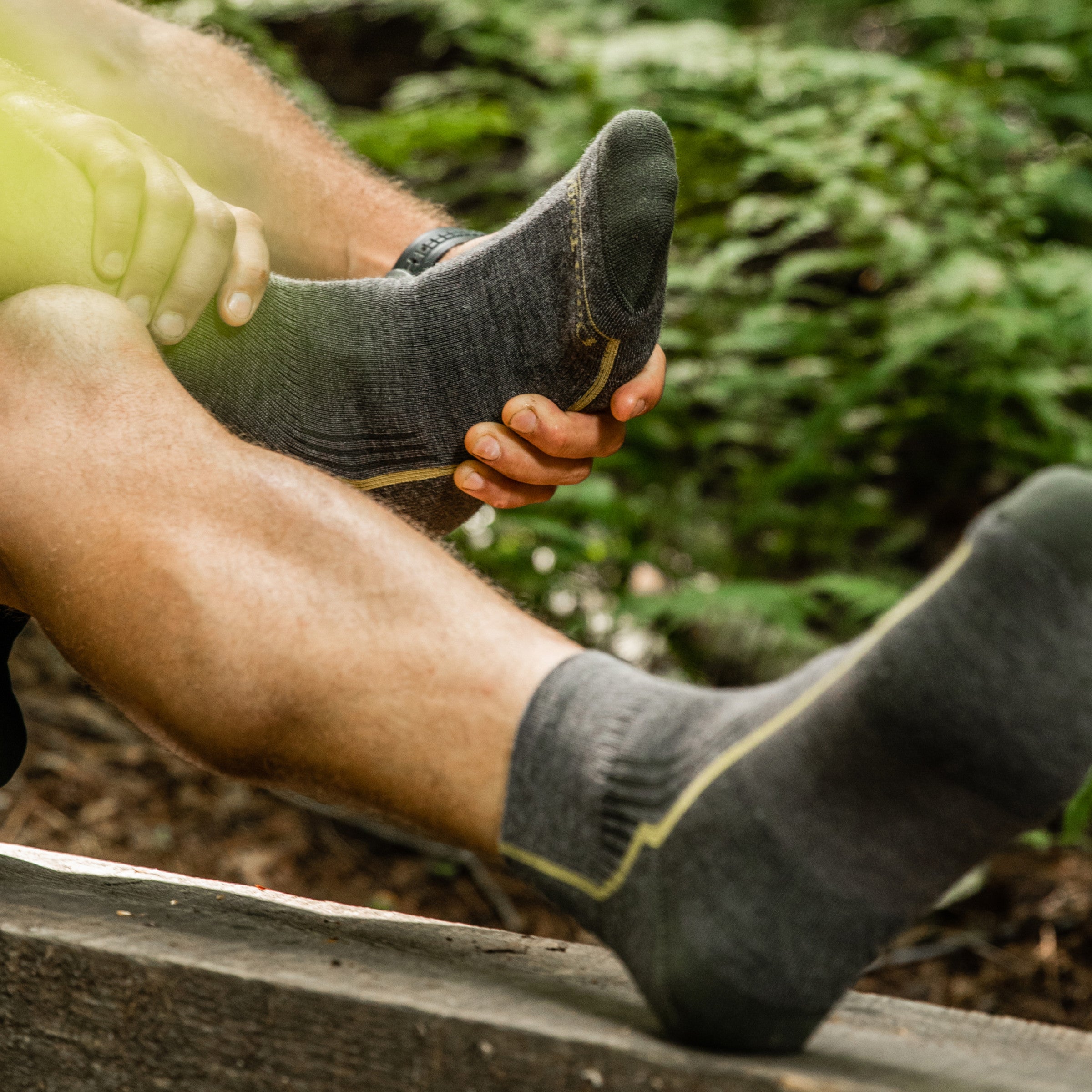 Hiker inspecting his feet, which look good cause he's wearing the men's quarter hiking socks