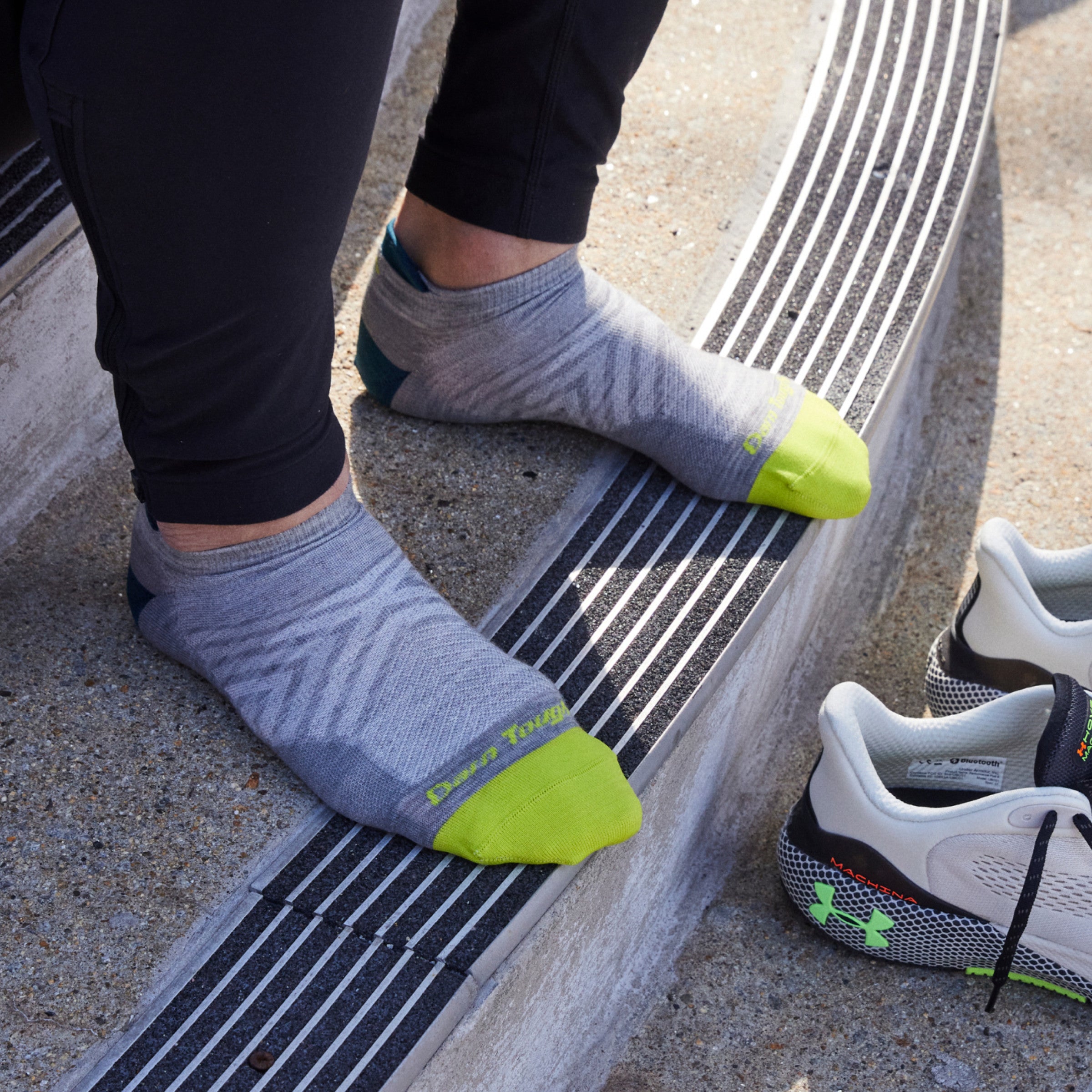 Close up shot of model sitting on concrete steps and wearing 1033 socks in Gray colorway without shoes