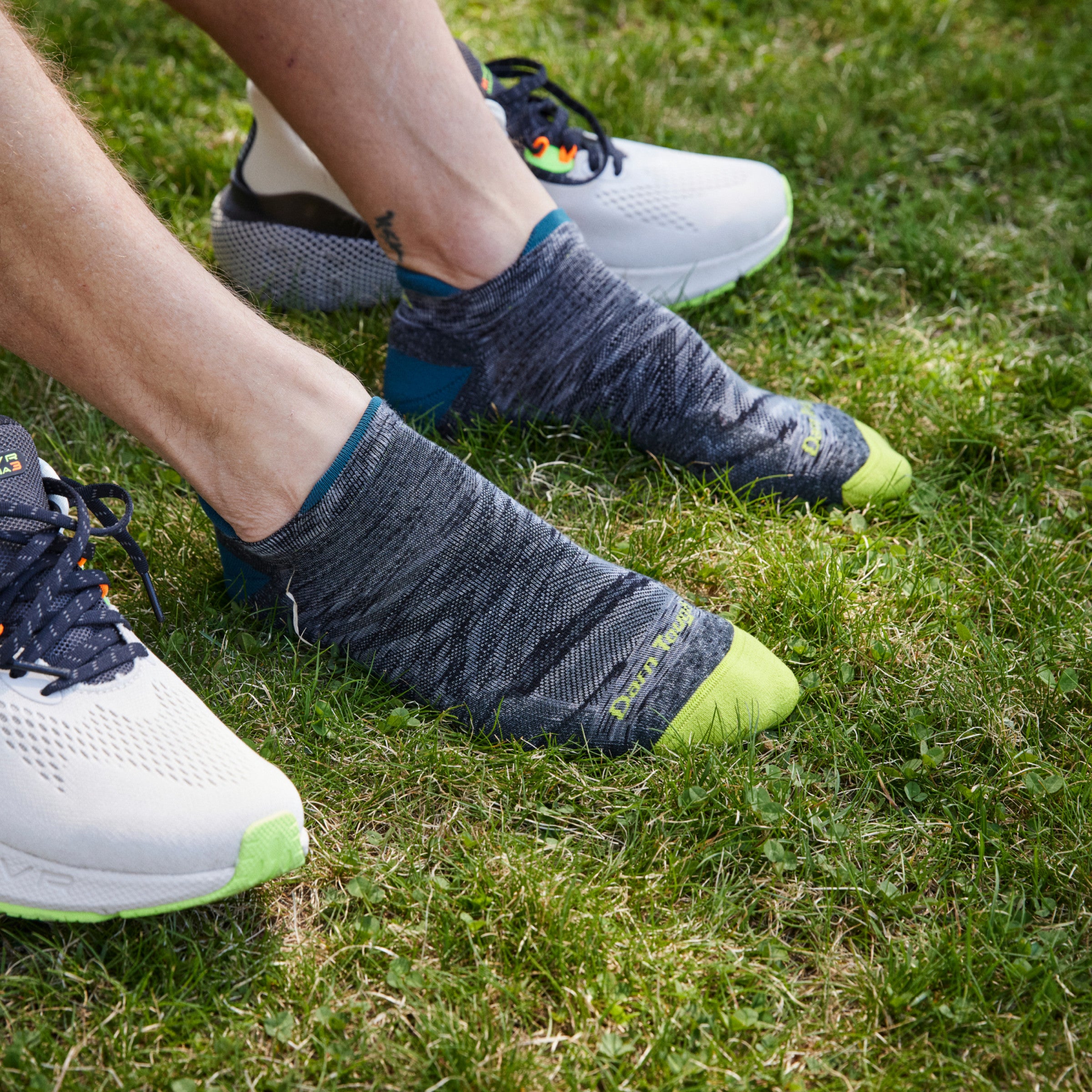 Close up shot of model sitting on grass wearing 1039 socks in Comet colorway without shoes on