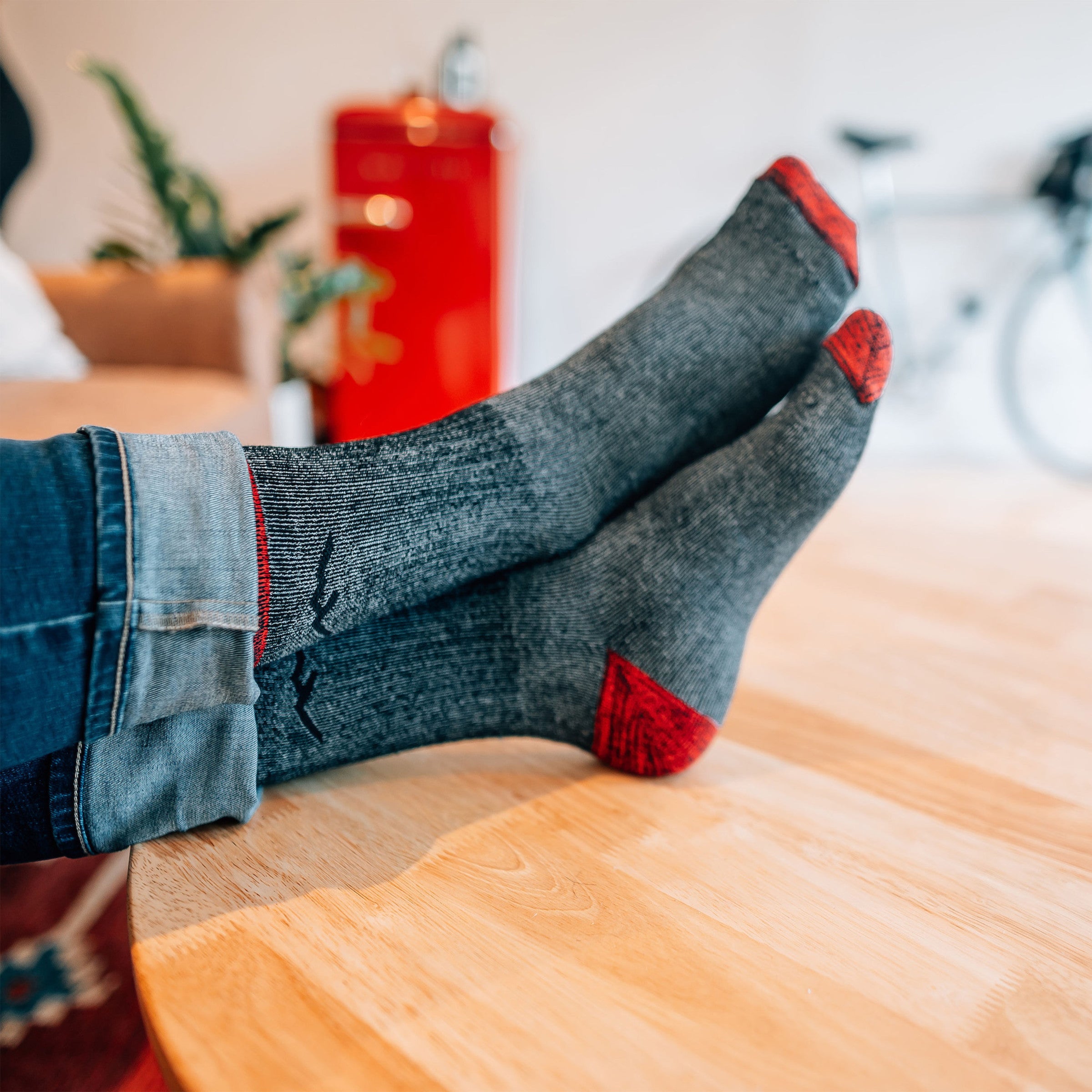 Model with hiis feet up on a coffee table wearing the men's mountaineering micro crew hiking sock in smoke