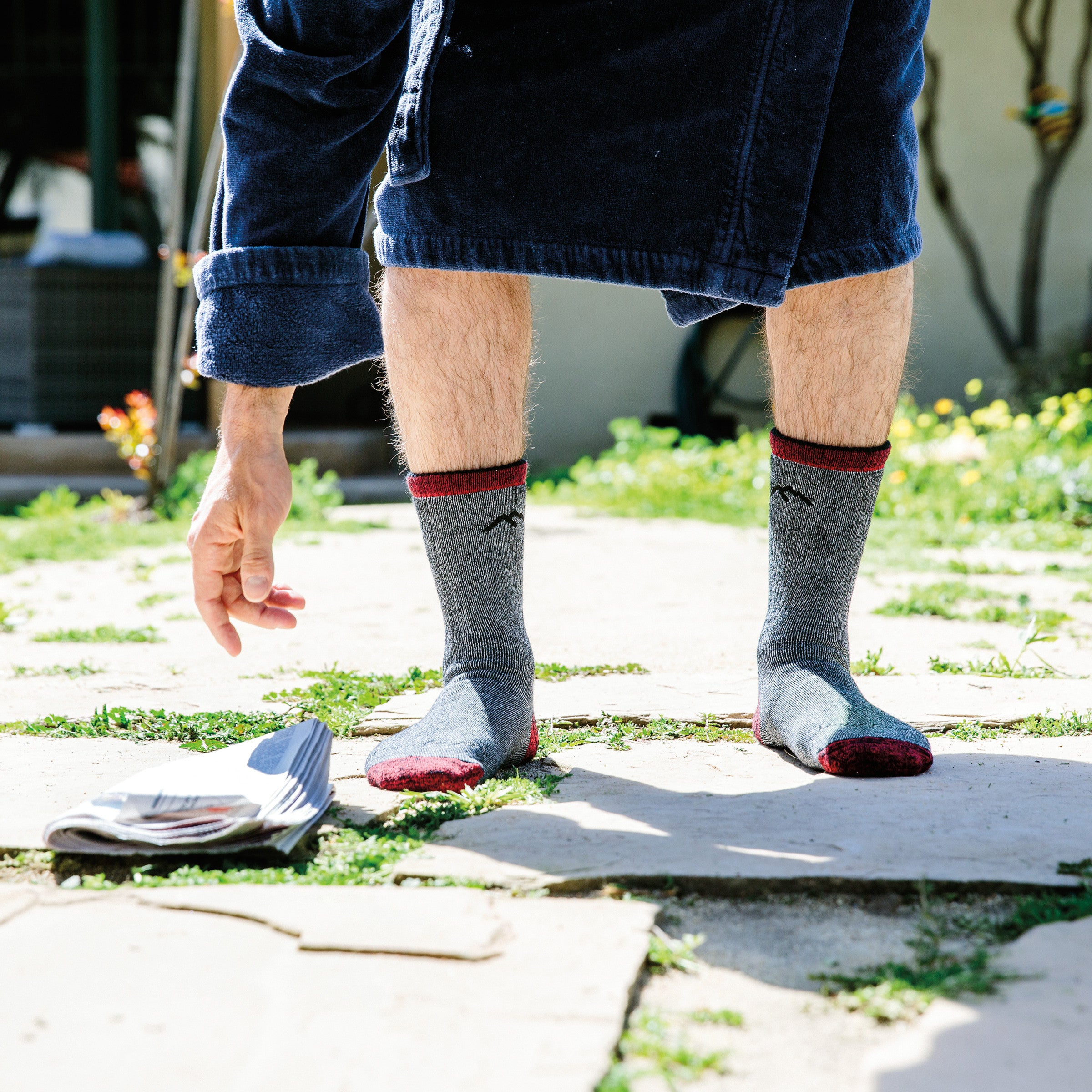 Man bending down to pick up the newspaper wearing Men's Mountaineering Micro Crew Heavyweight Hiking Socks in Smoke