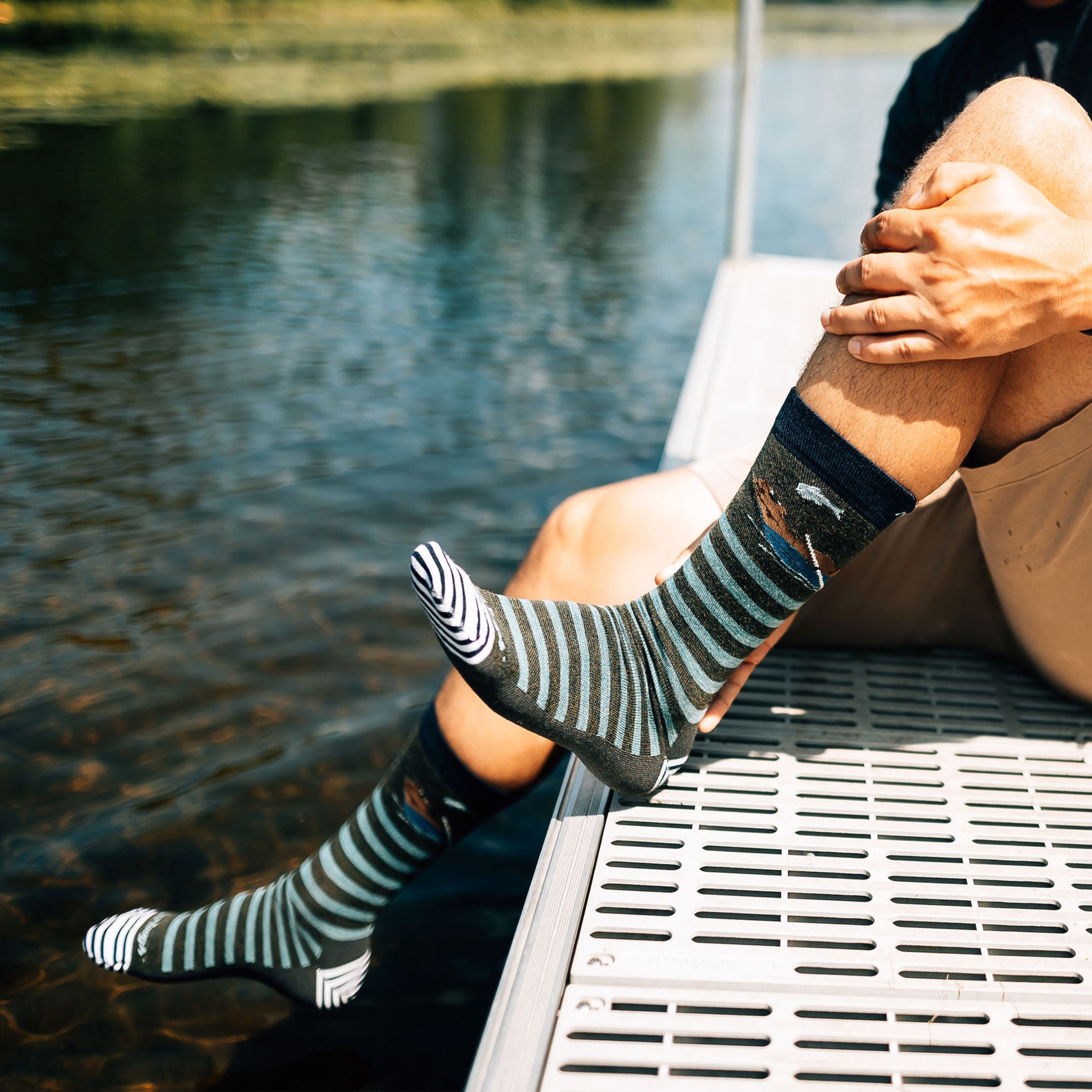Close up shot of model sitting on a lake wearing the men's animal haus crew lifestyle sock in forest green