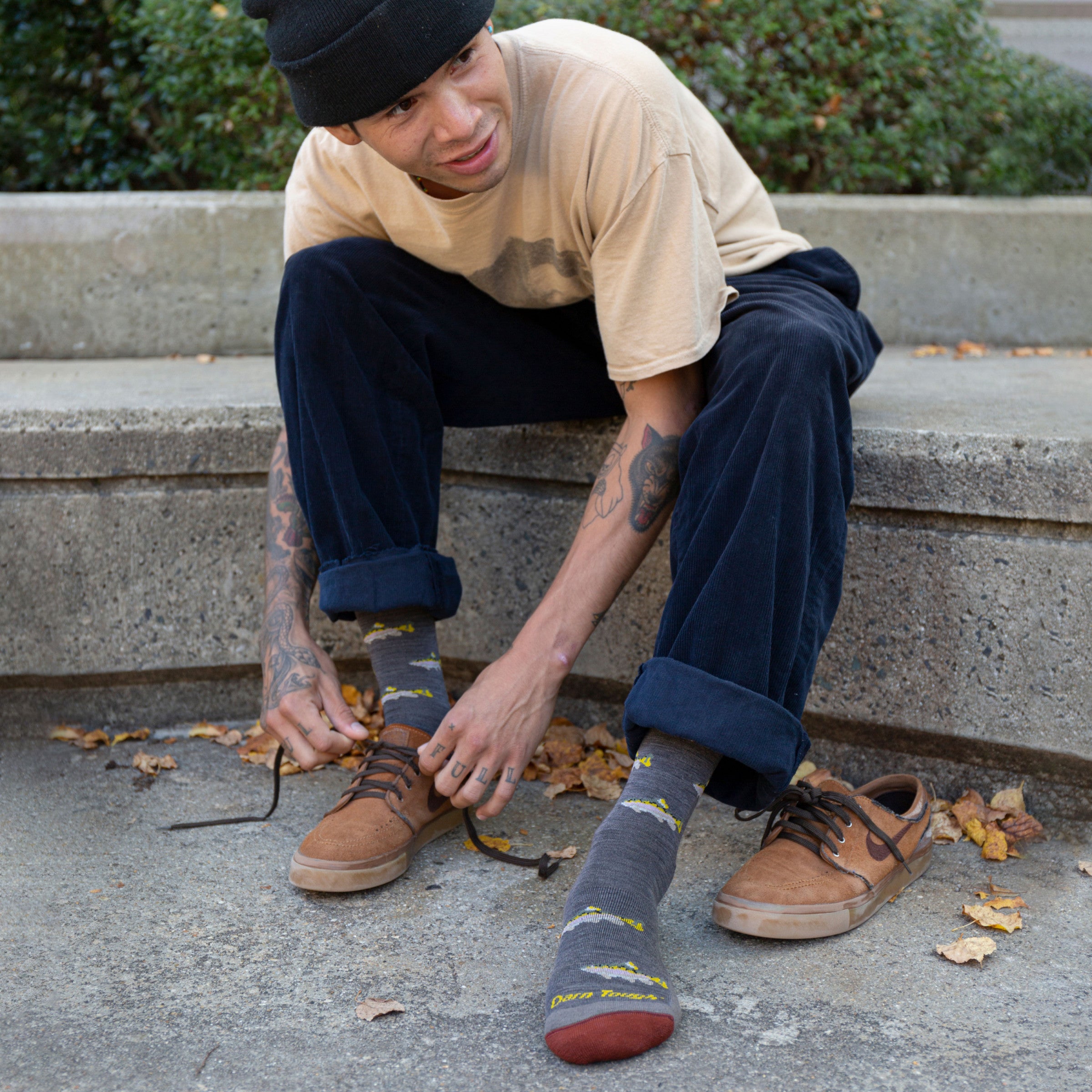 Man tying sneaker shoe laces while wearing the spey fly socks with fish on them