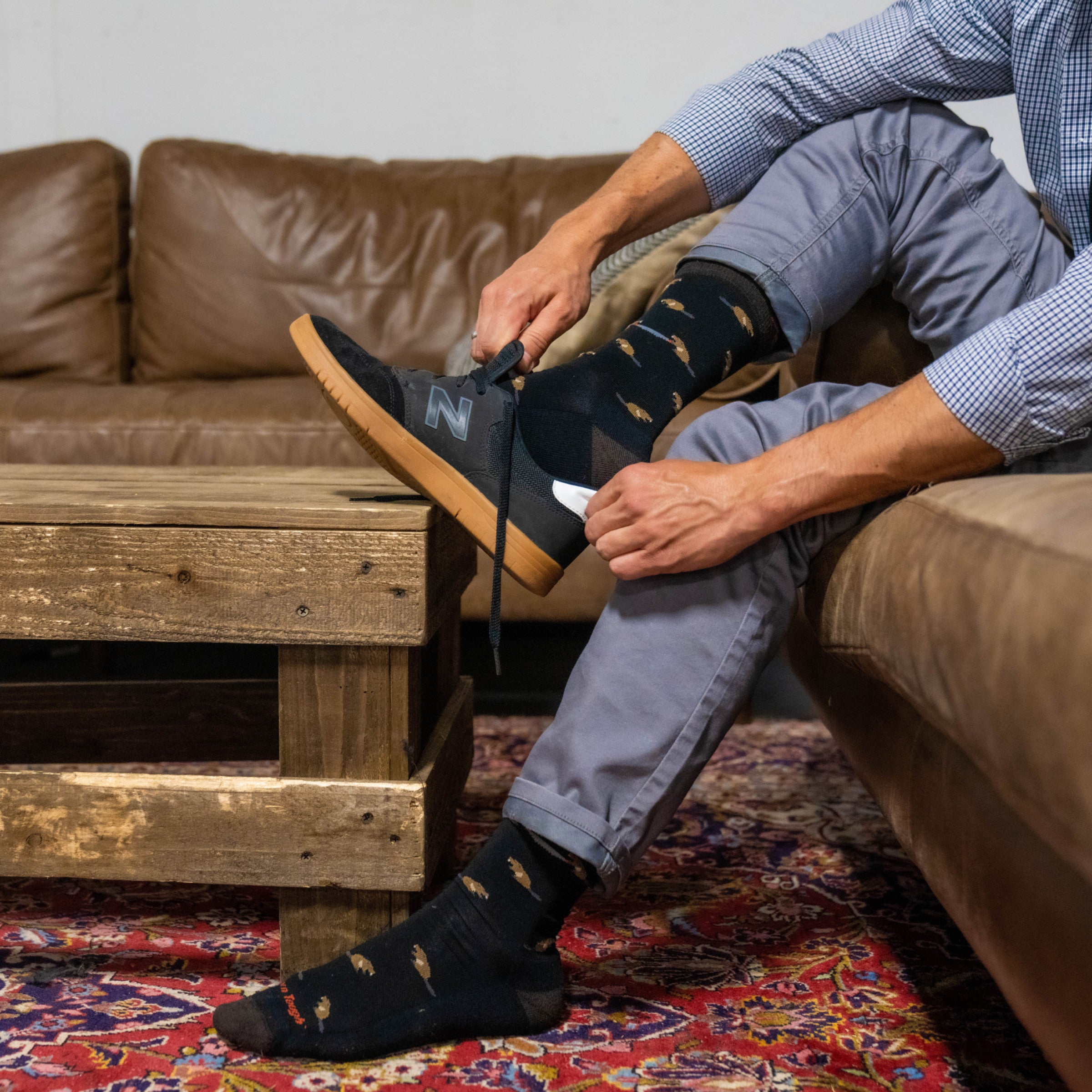 Close up on model sitting on a couch putting shoes on wearing the 6107 Sawtooth Lifestyle in Black