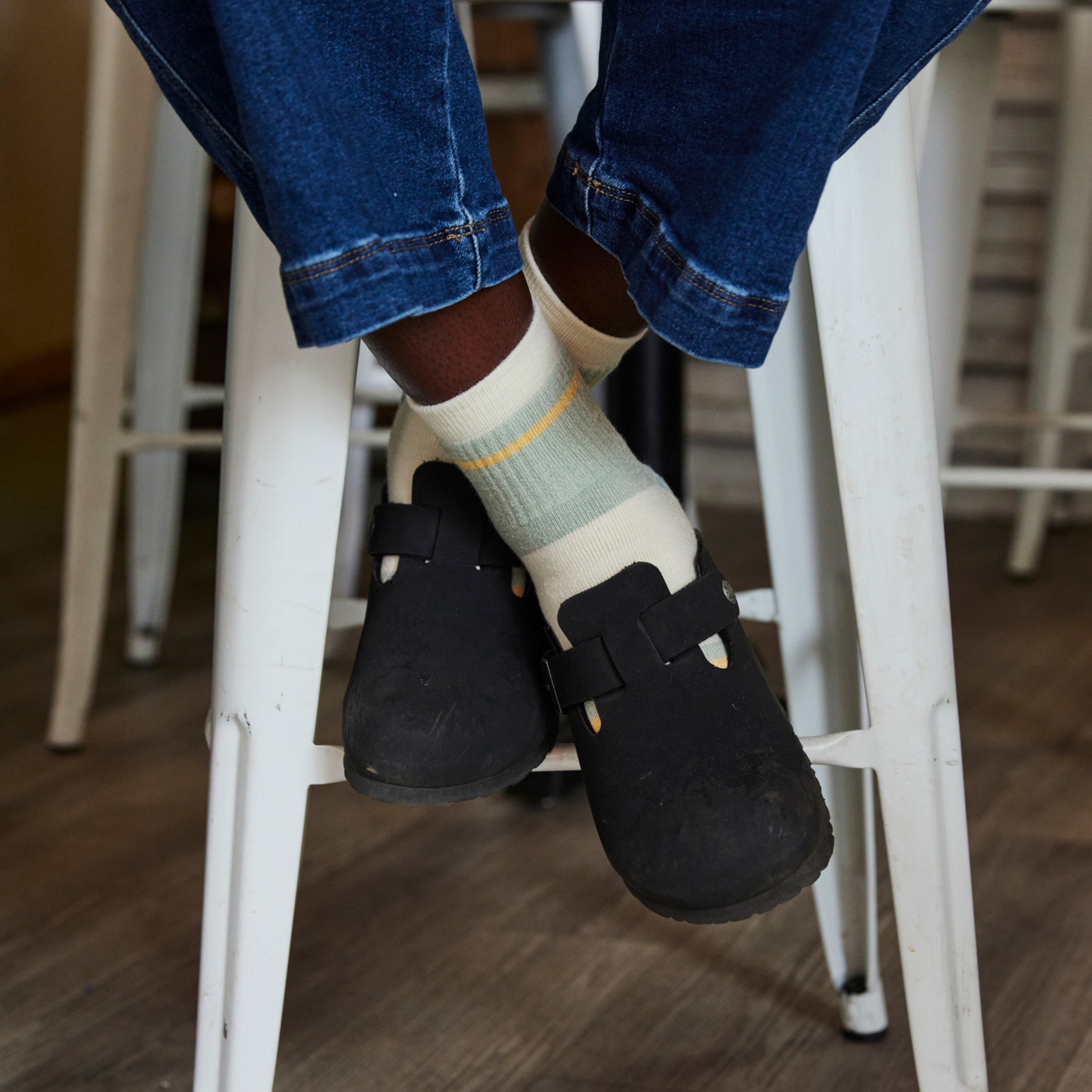 close up of model feet crossed on stool wearing the 6117 pear and clogs