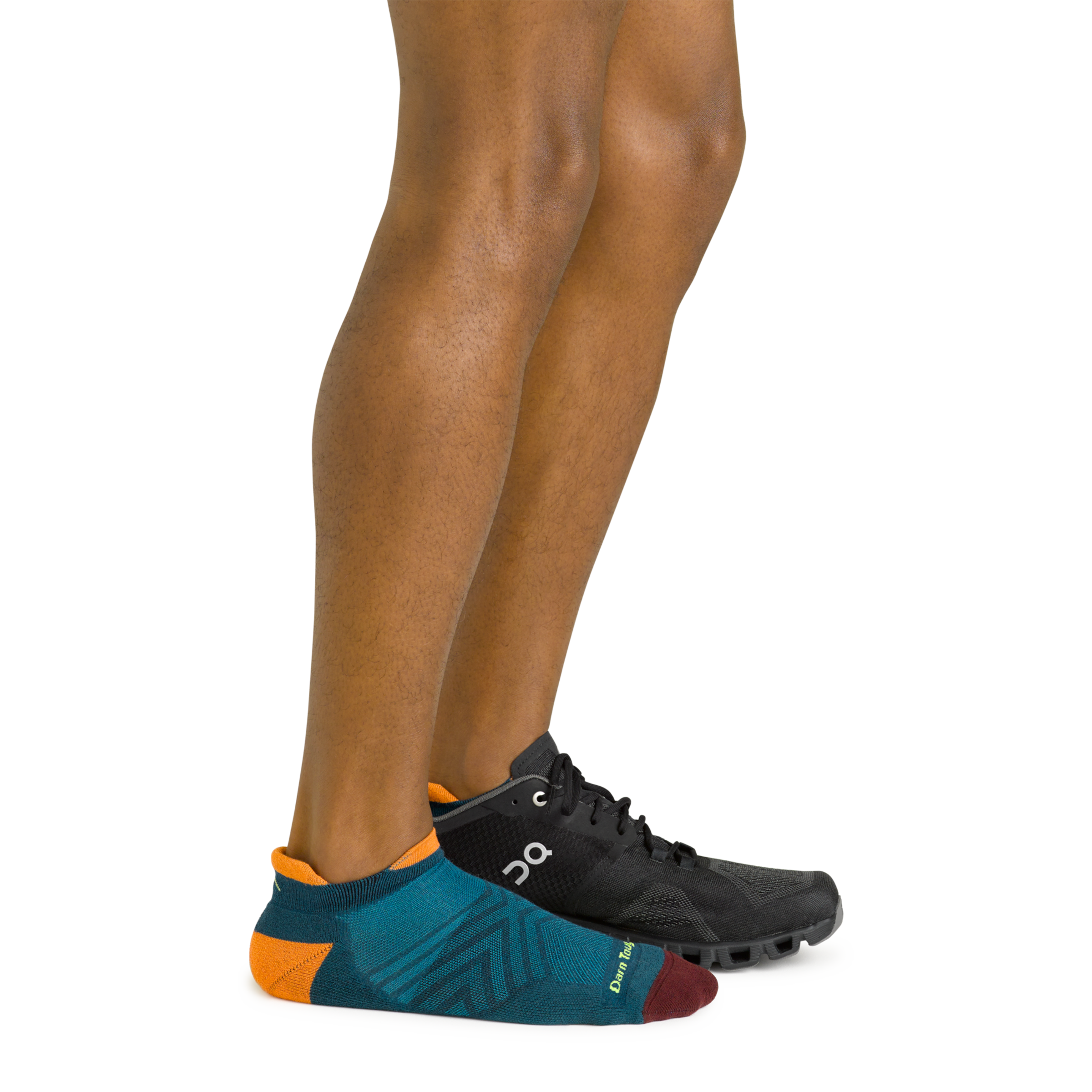 Side shot of model wearing the men's no show tab running sock in dark teal with a black sneaker on his left foot