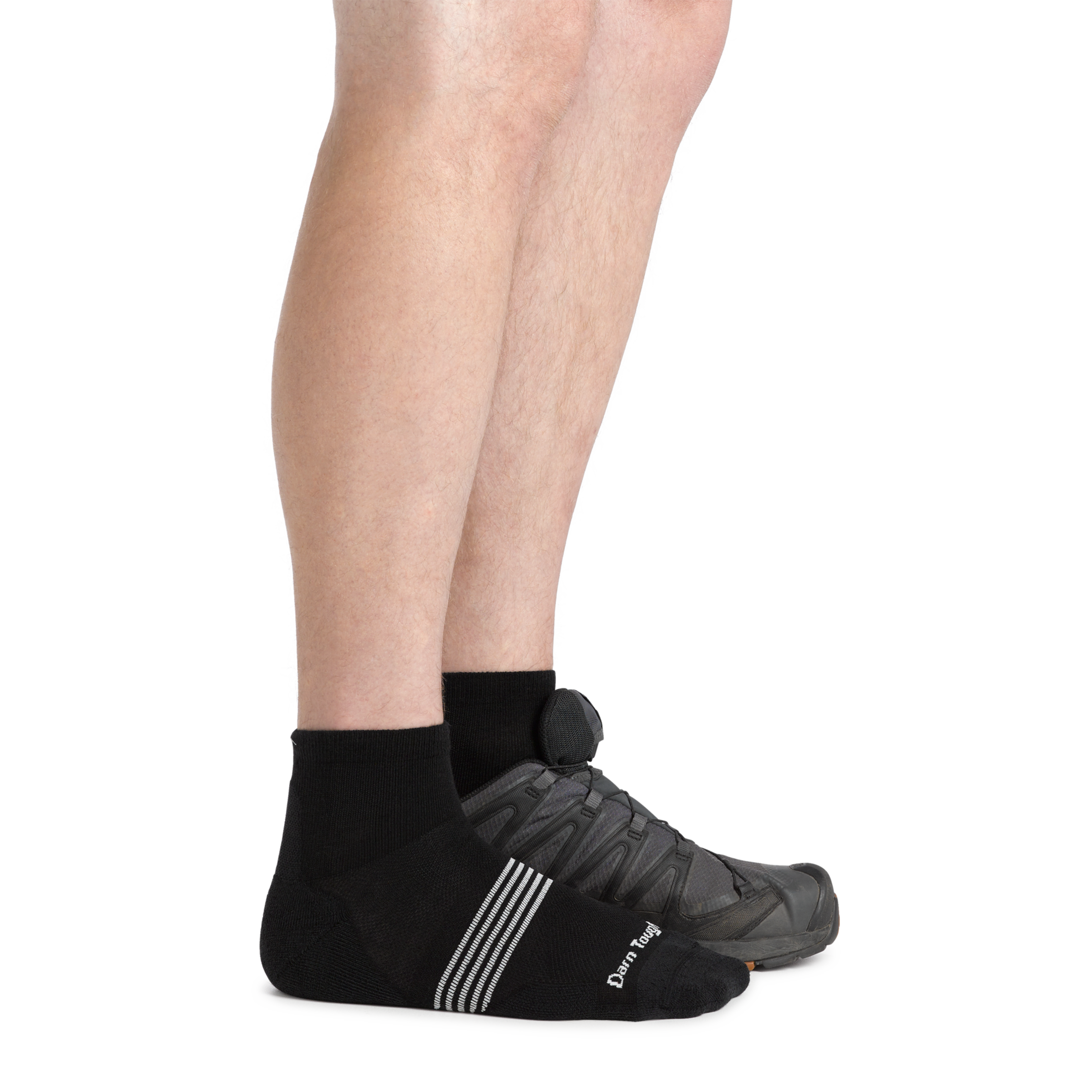 Side studio shot of model wearing men's element quarter running sock in black with gray sneaker on left foot