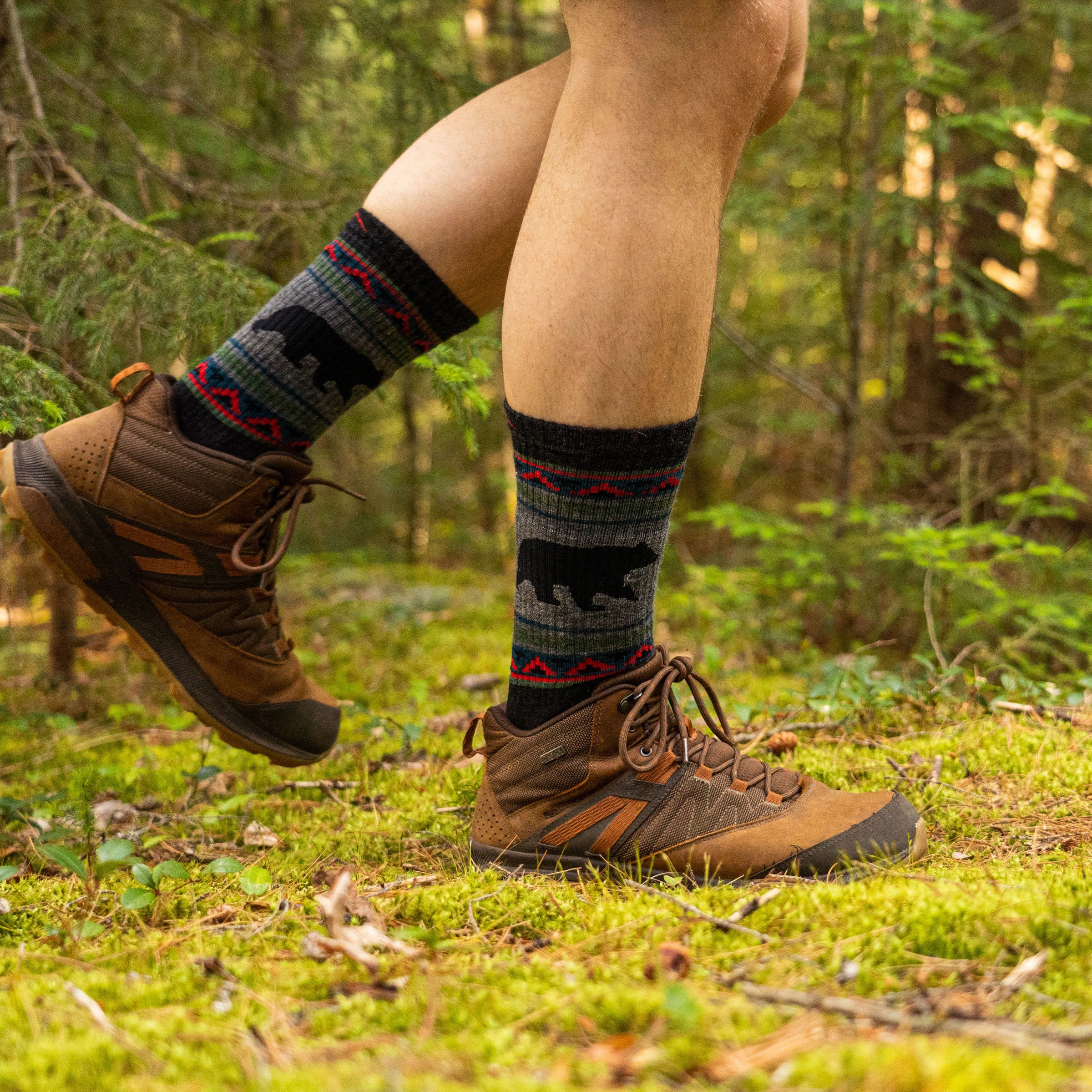 Man walking on a mossy trail in a forest, wearing hiking boots and VanGrizzle Boot Midweight Hiking Sock in Charcoal