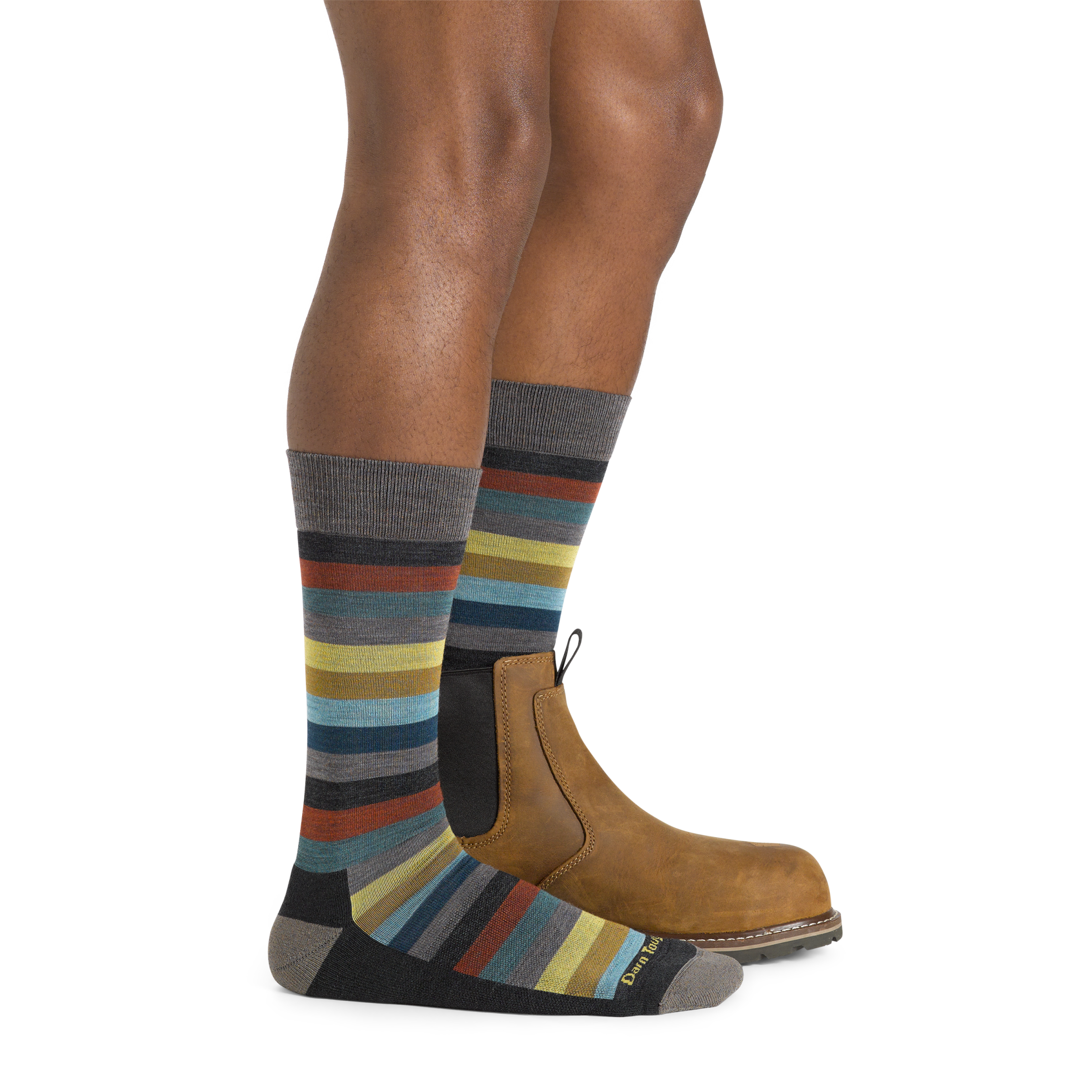 Side studio shot of model wearing men's merlin crew lifestyle sock in charcoal with brown boot on left foot