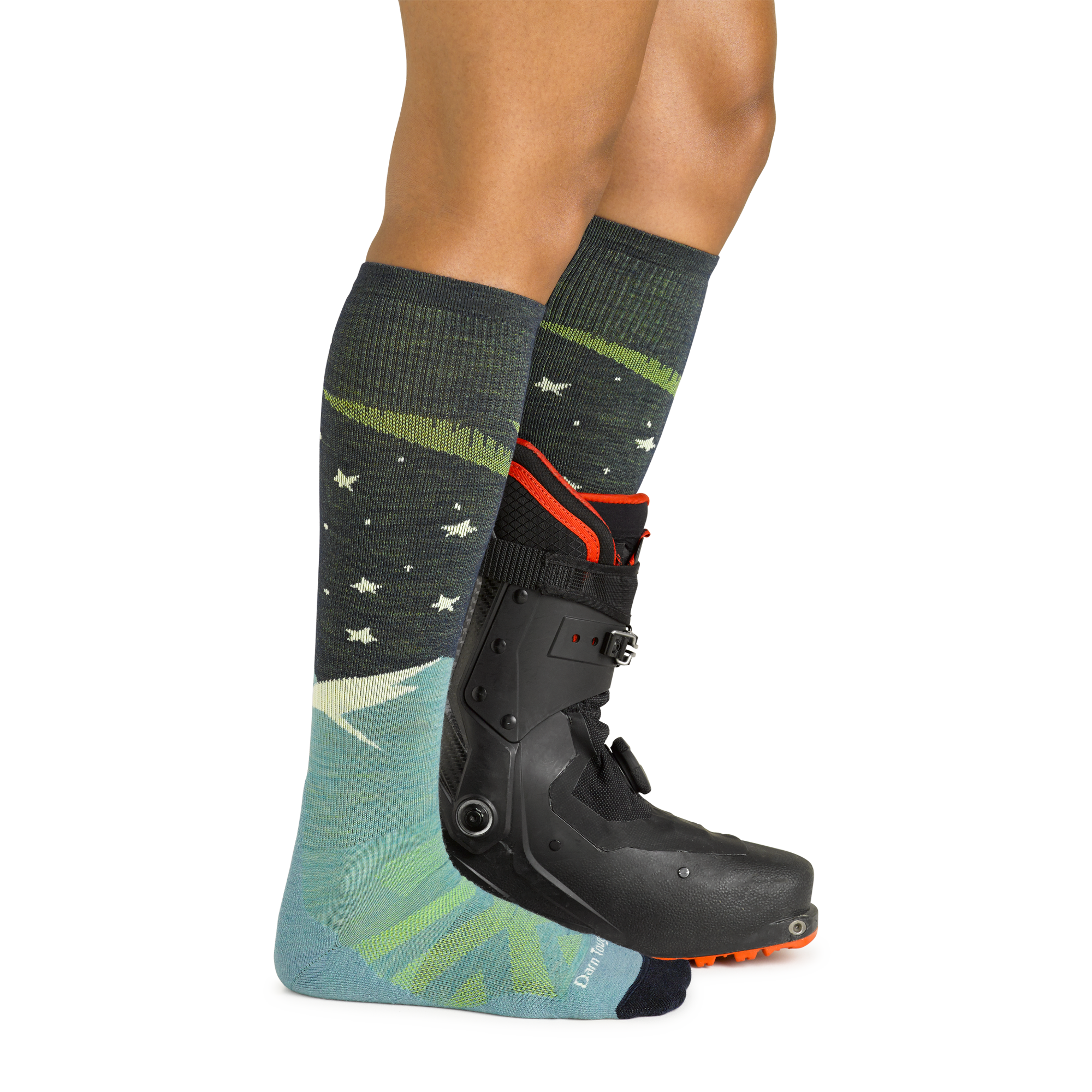 Model wearing women's aurora over-the-calf lightweight snow sock in aqua with black ski boot on left foot