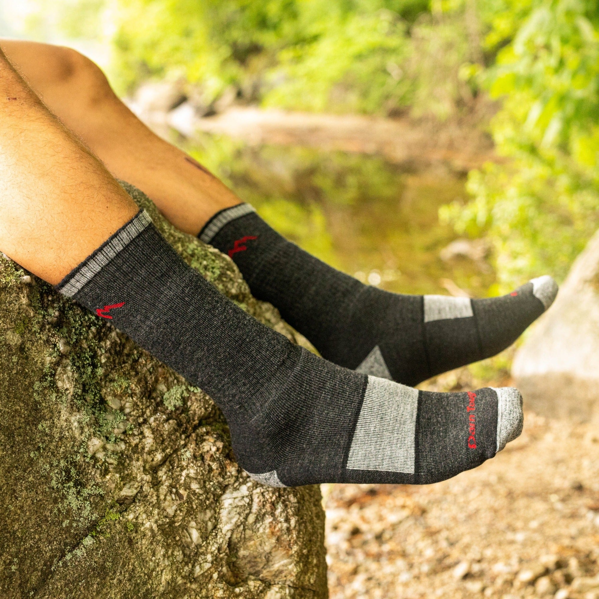 Close up shot of model sitting on a rock wearing the men's 1405 boot hiking sock in black