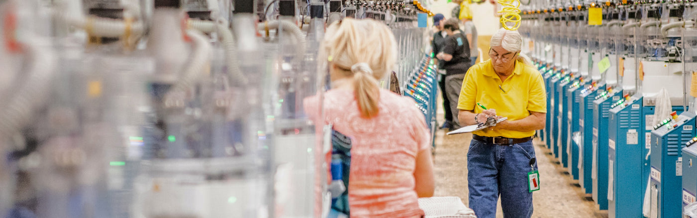 Darn Tough employees walking through the Mill, checking the machines and yarns