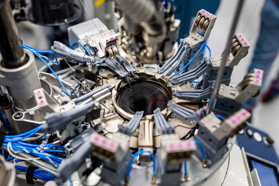 Closeup look at the inner workings of a Darn Tough knitting machine as it makes a sock