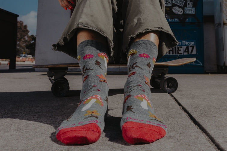 Feet wearing women's socks with mushrooms and flowers on them