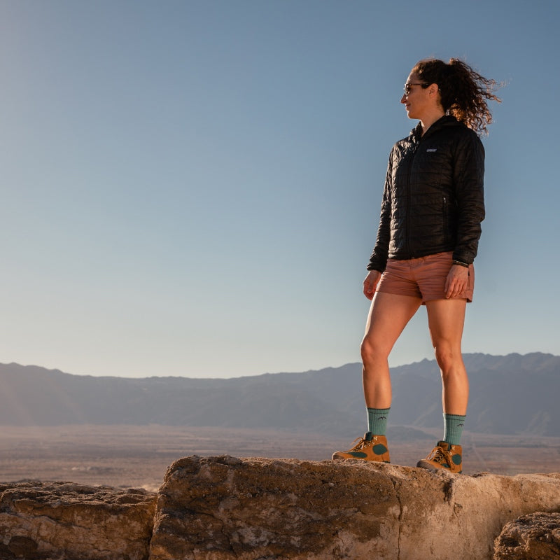 Woman wearing Darn Tough hiking socks standing on a dramatic outlook