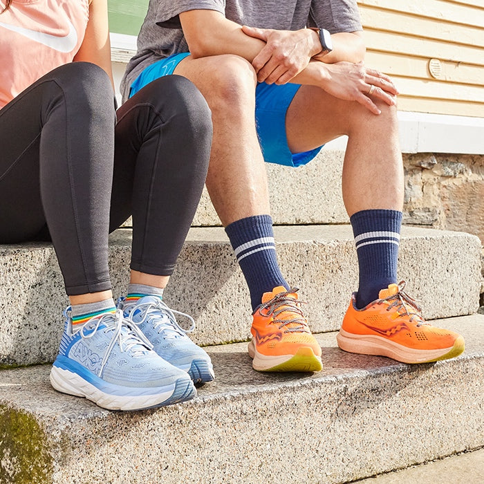 Two people seated on stairs with running socks and shoes on, about ready to start their run