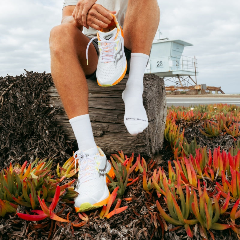 Runners by the seaside wearing white shoes and solid white Darn Tough run socks