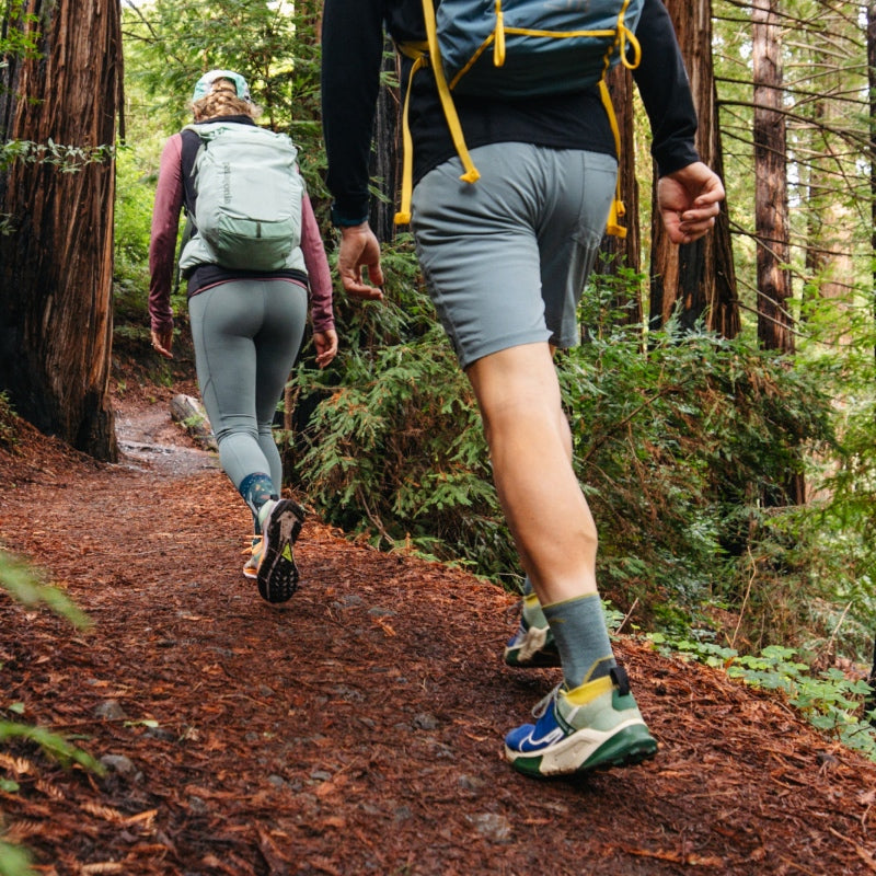 Two hikers walking up a trail wearing Darn Tough hiking socks