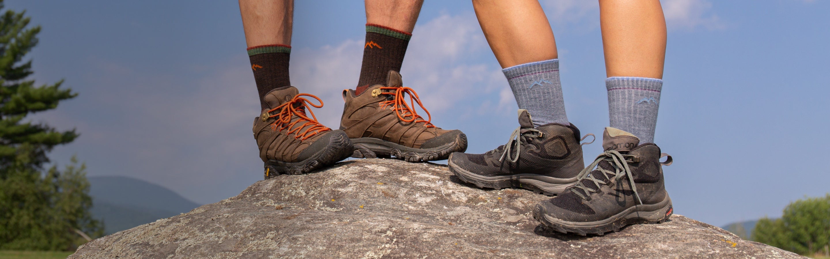 Two hikers standing on summit wearing Darn Tough hiking socks