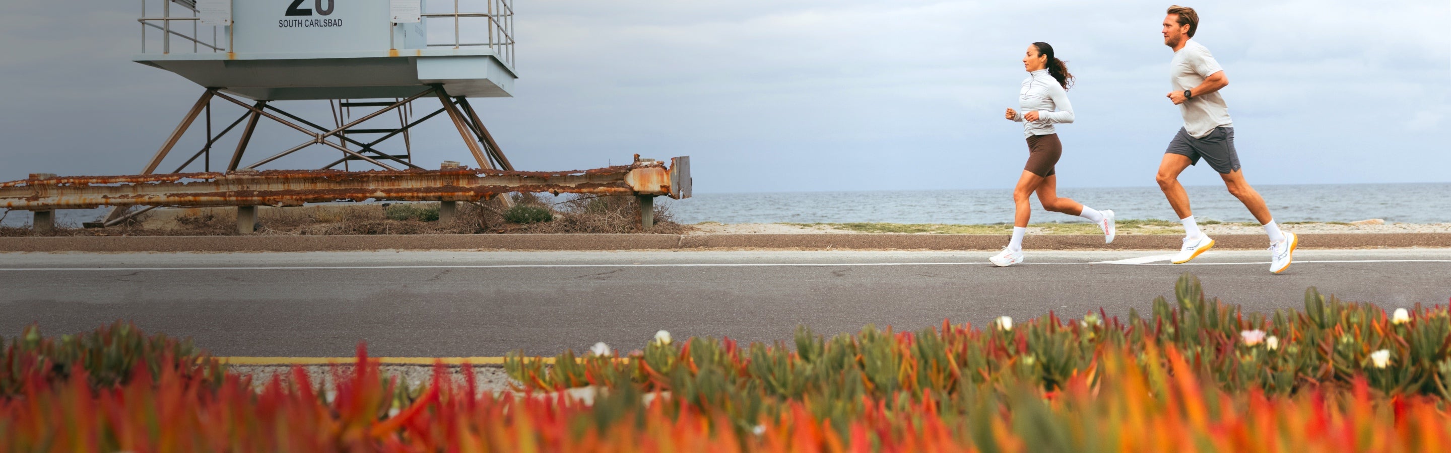 Runners by the seaside wearing white shoes and solid white Darn Tough run socks