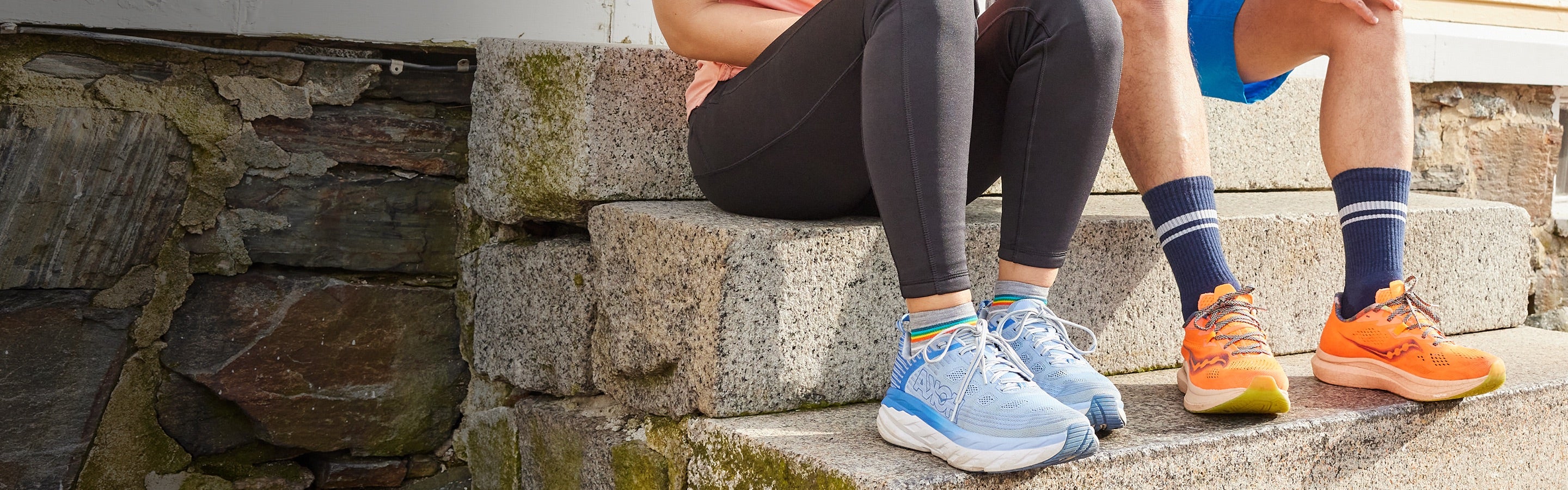 Two people seated on stairs with running socks and shoes on, about ready to start their run