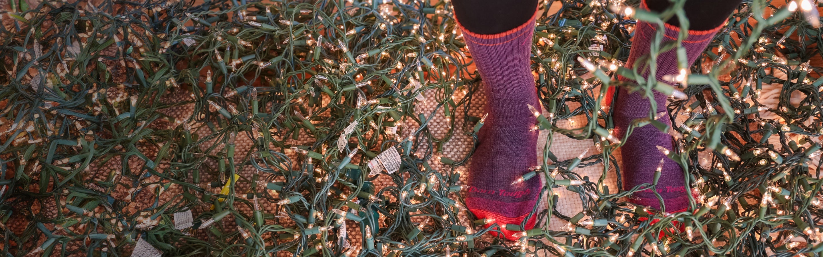 A pair of feet in Darn Tough socks standing in a giant tangle of holiday lights