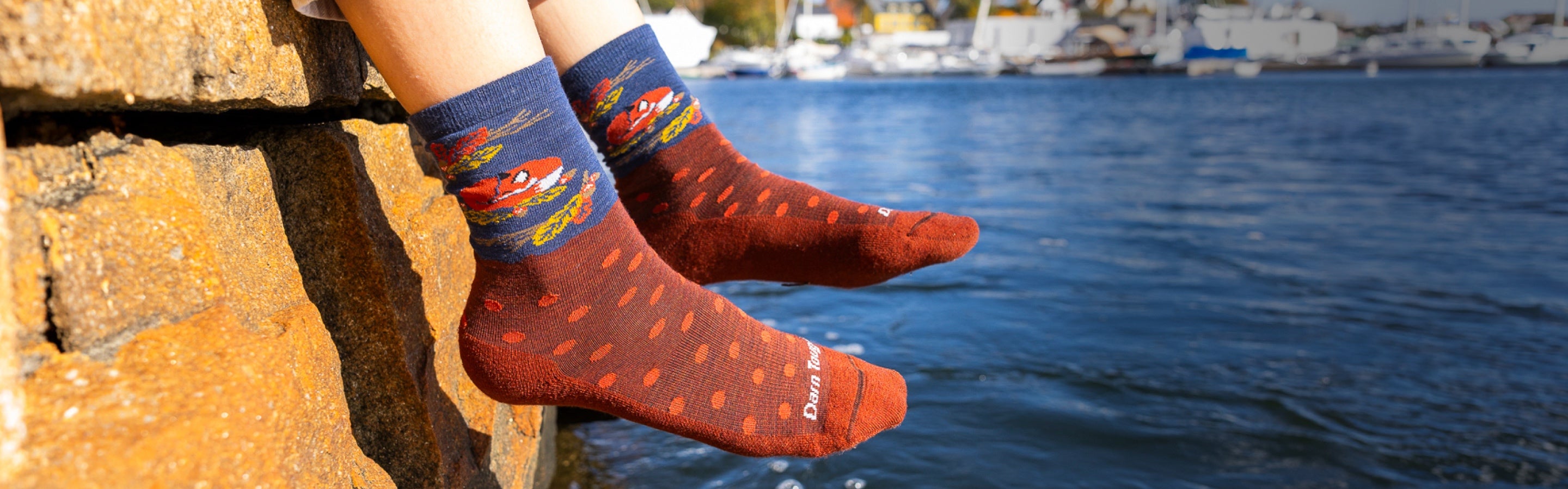 Feet hanging out over the water wearing new socks with polka dots and a sleeping fox
